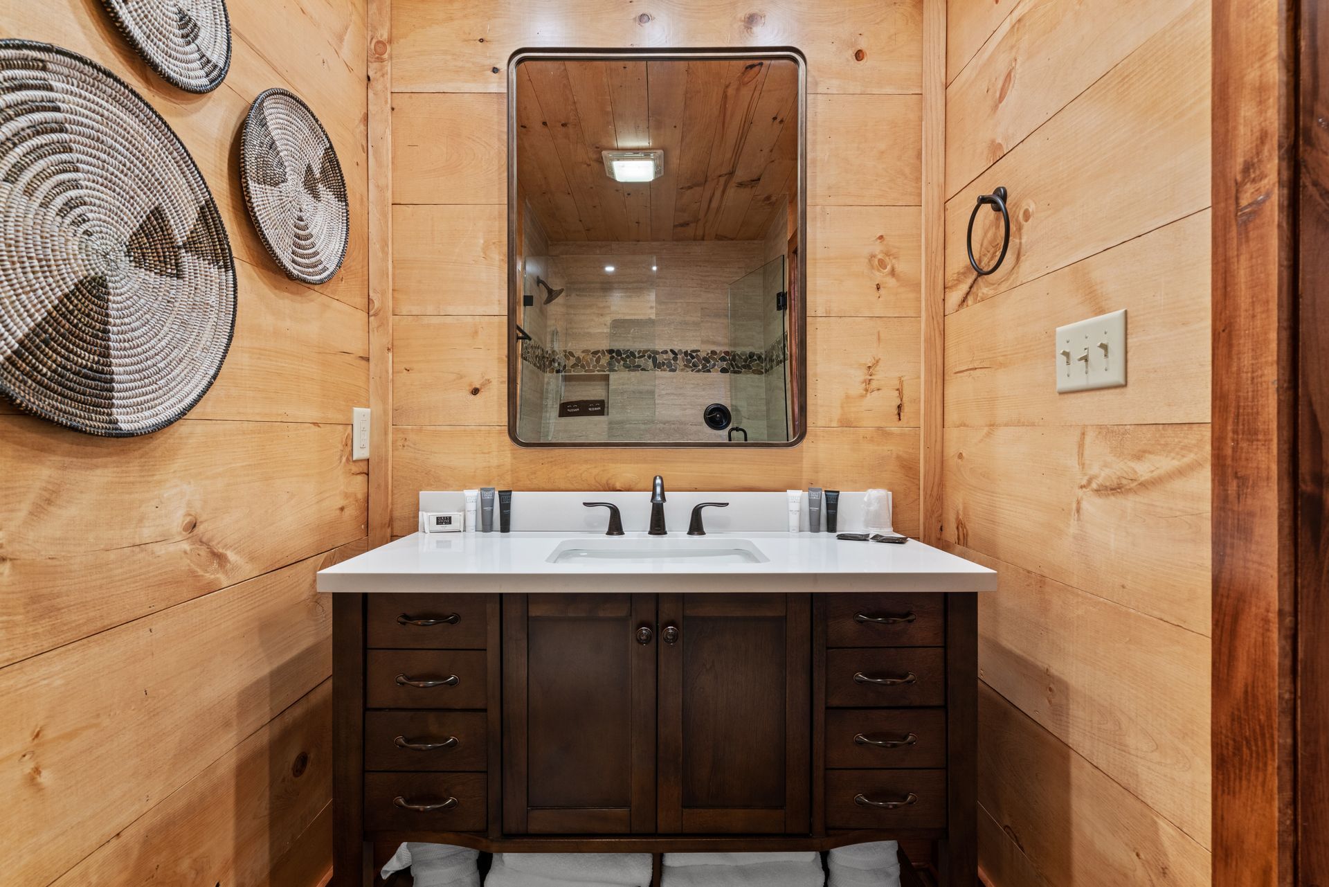 A bathroom with a sink , mirror and wooden walls.