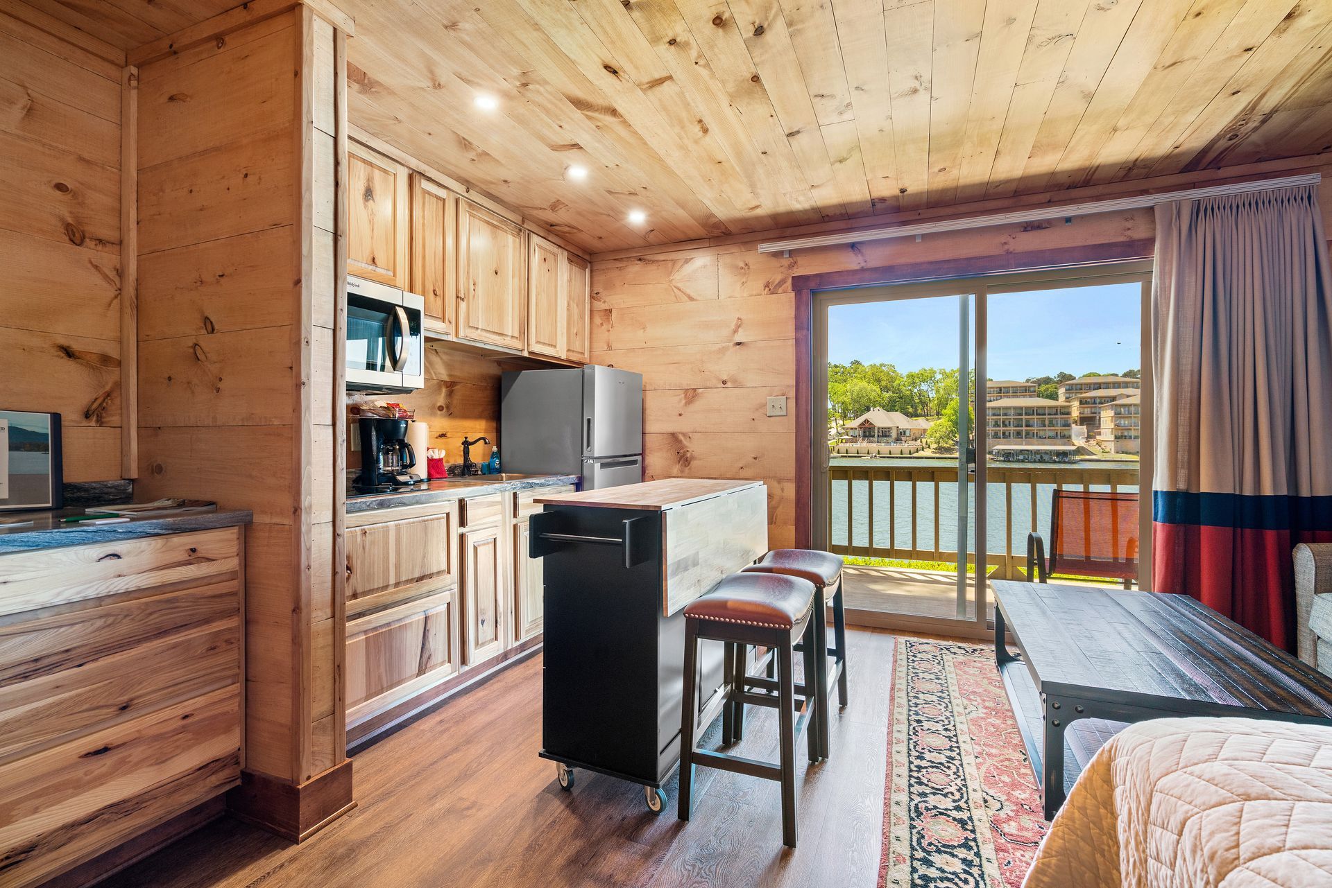 A living room with a sliding glass door leading to a balcony and a kitchen.