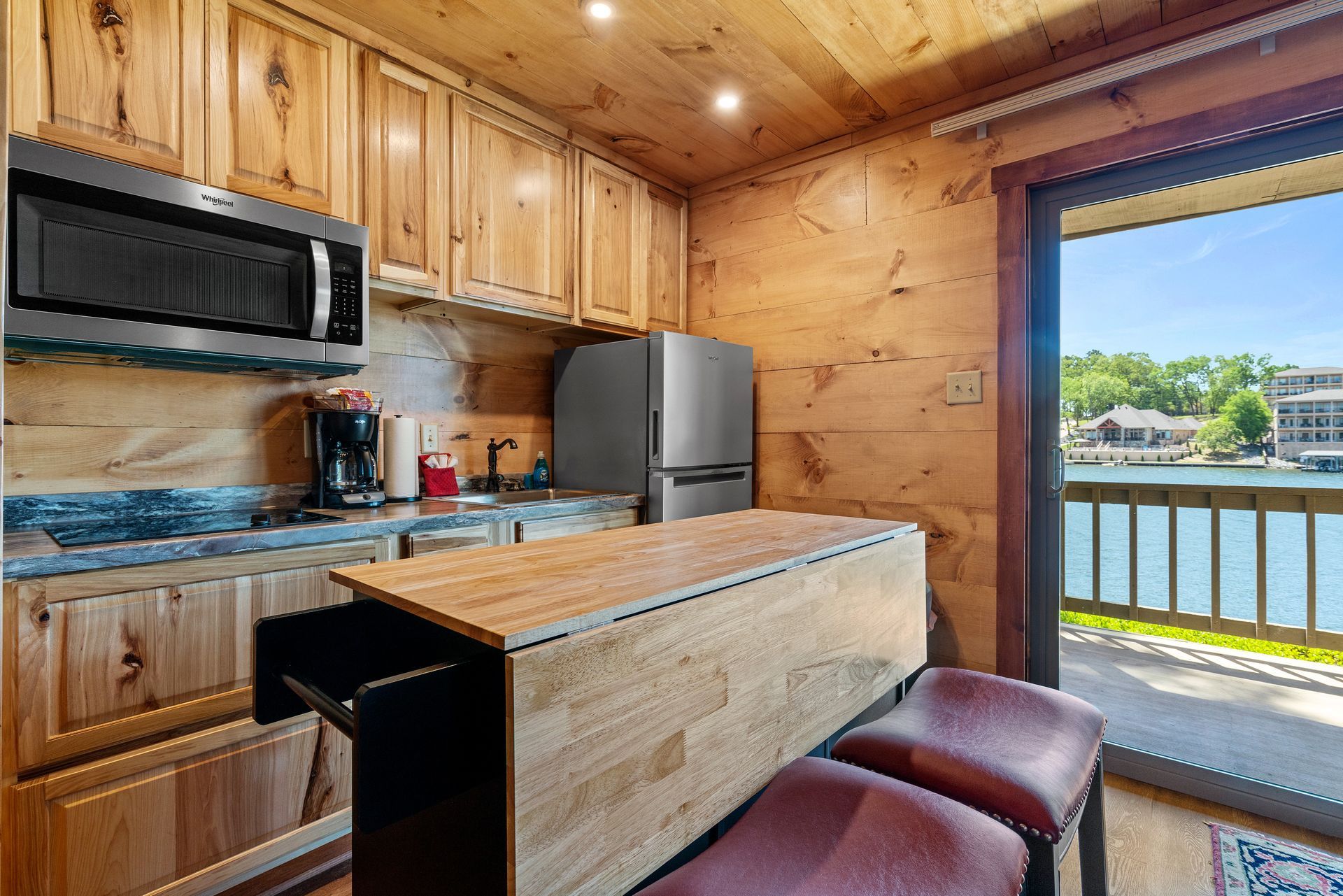 A kitchen with wooden cabinets , stainless steel appliances , a refrigerator and a microwave.