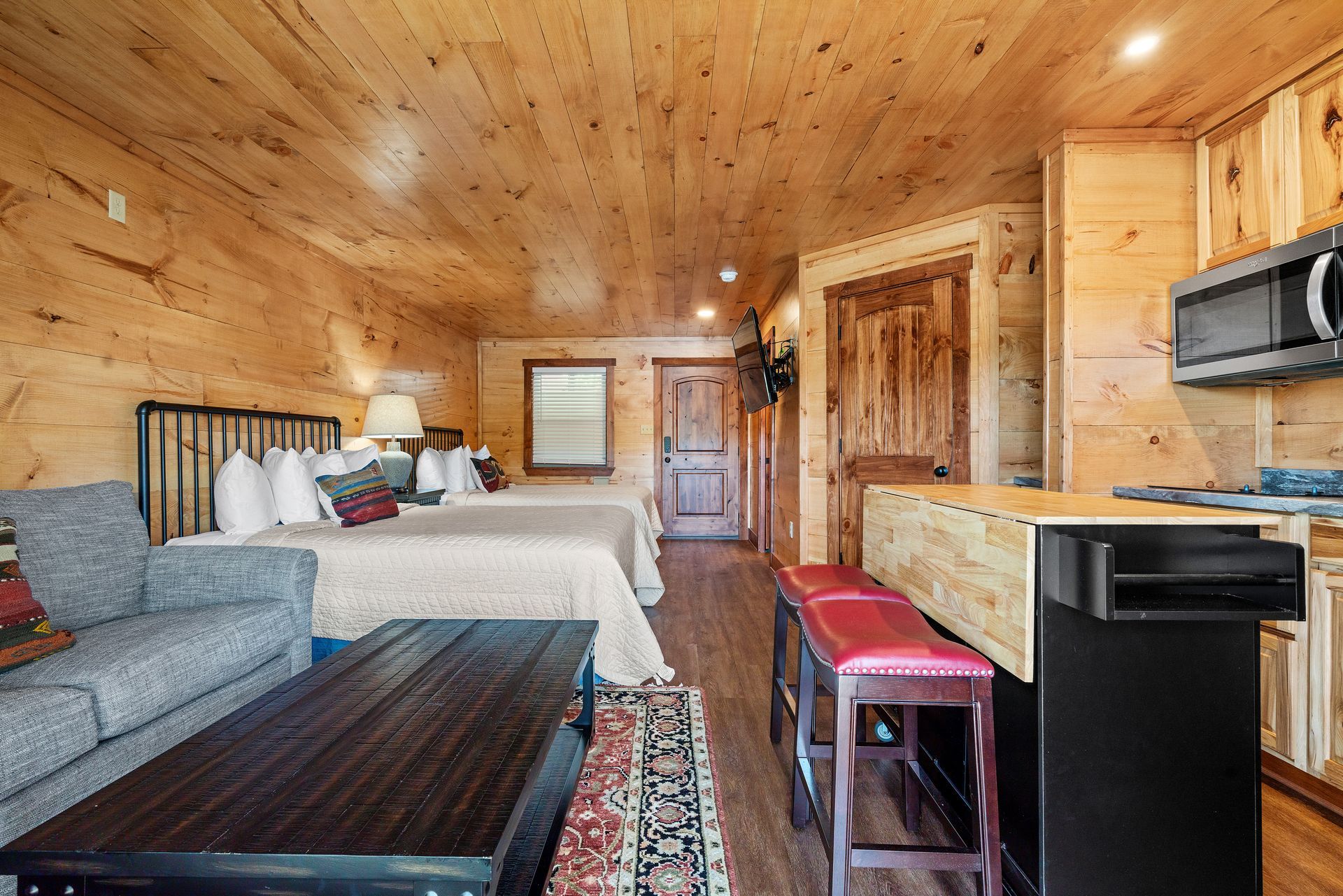 A cabin with two beds , a couch , a table and a kitchen.