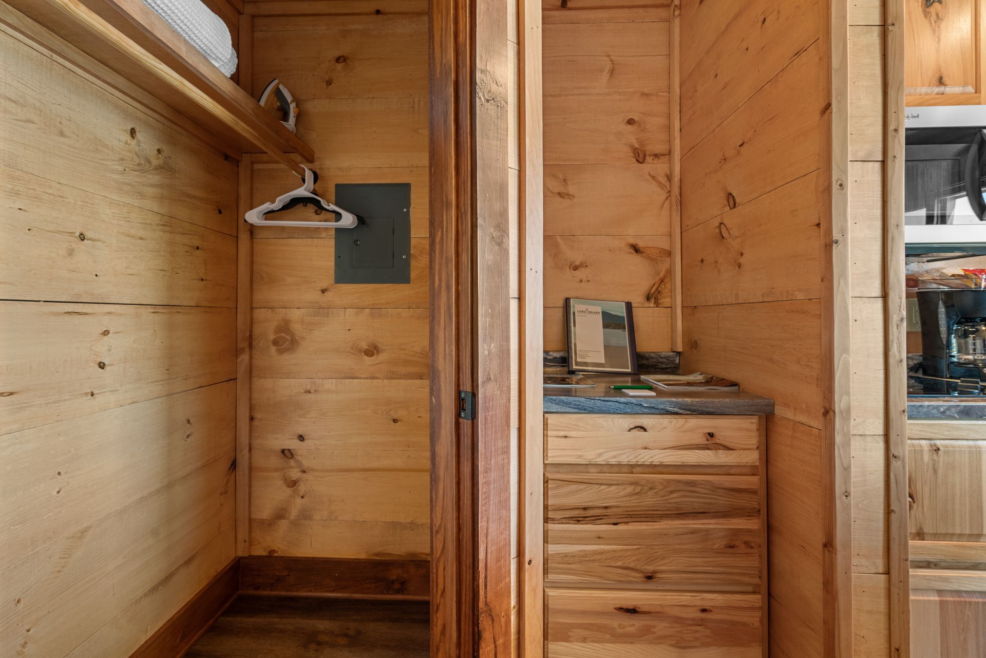 A wooden walk in closet with clothes hanging on the wall.