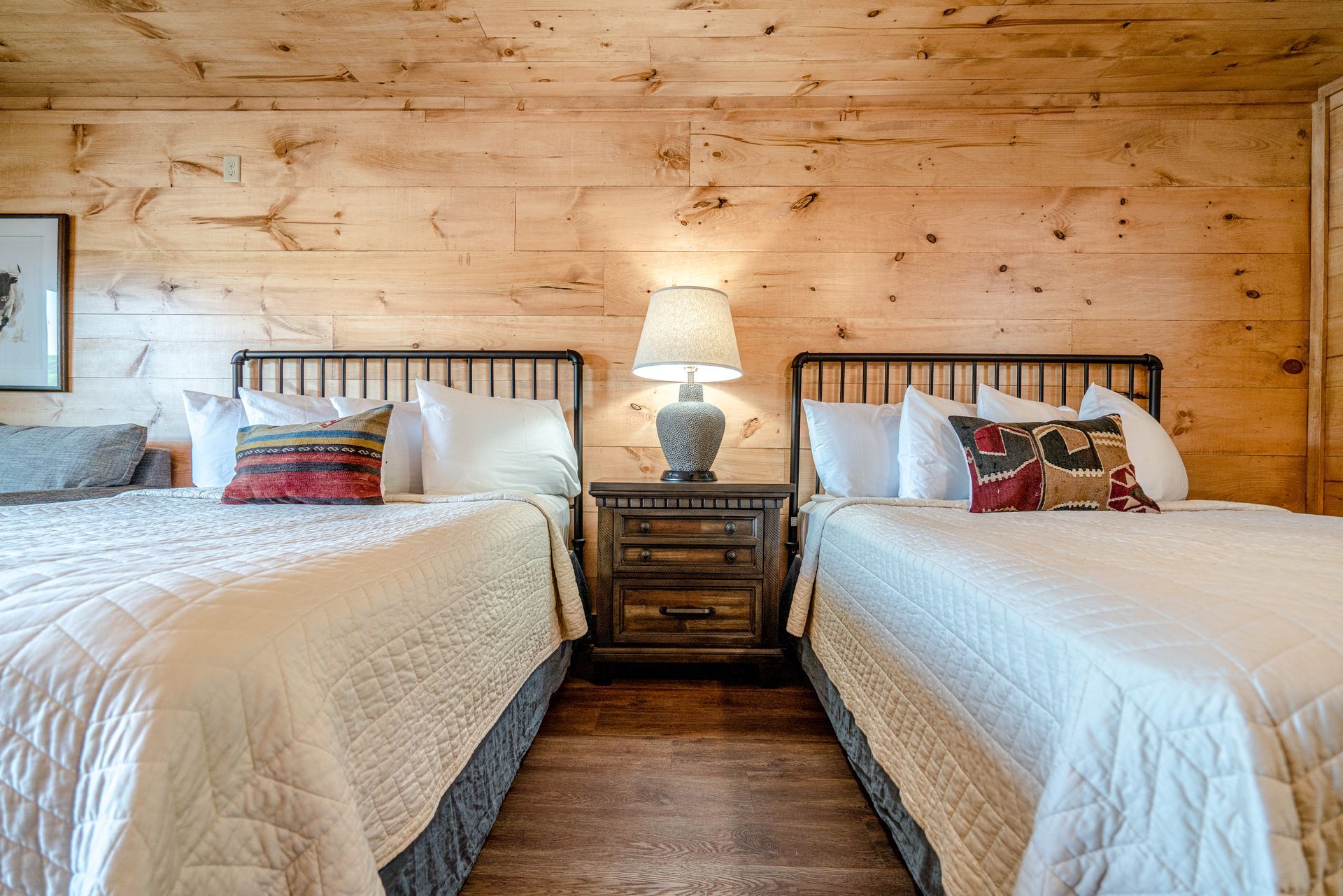 A bedroom with two beds and a wooden wall.