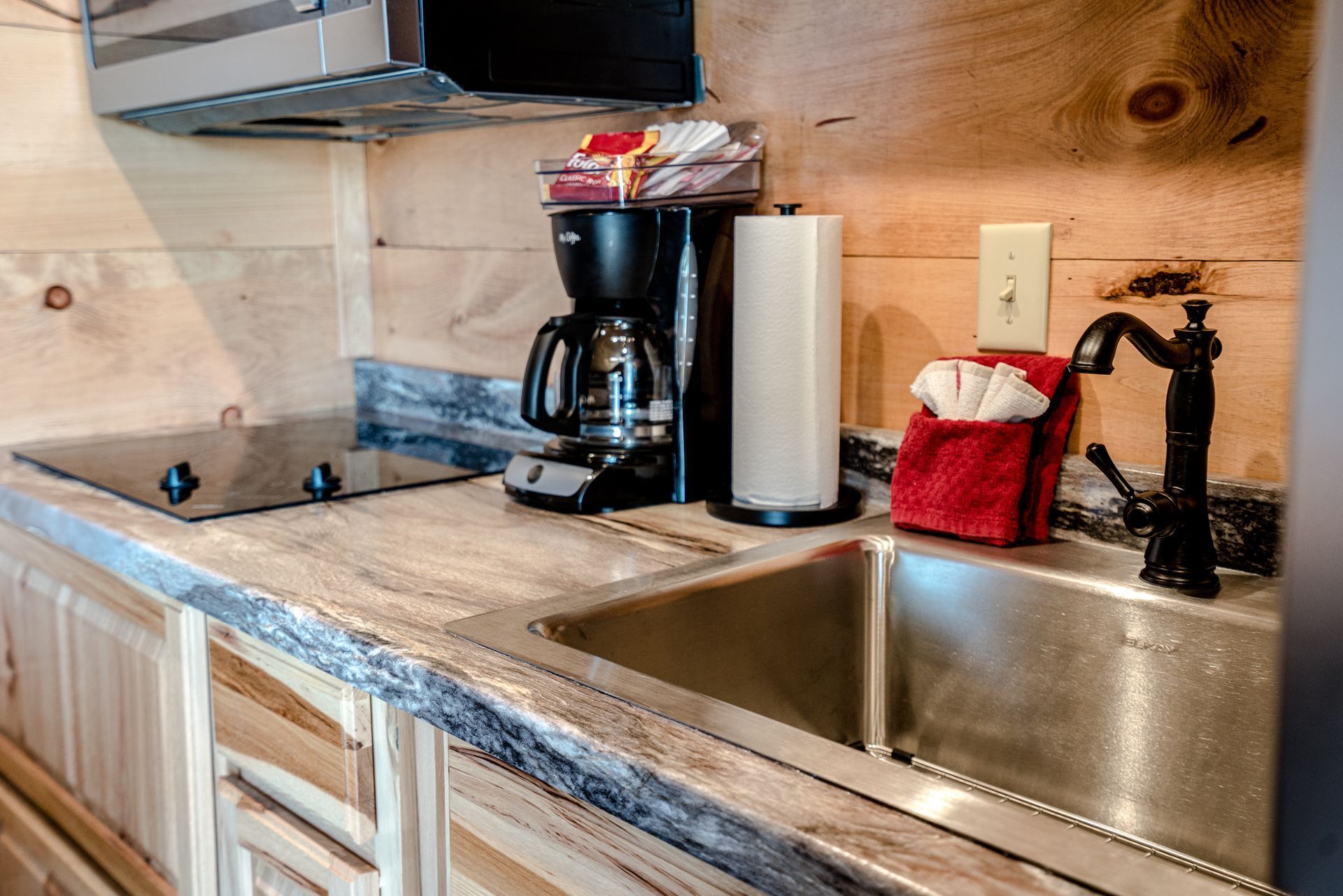 A kitchen with a sink , coffee maker , and stove.