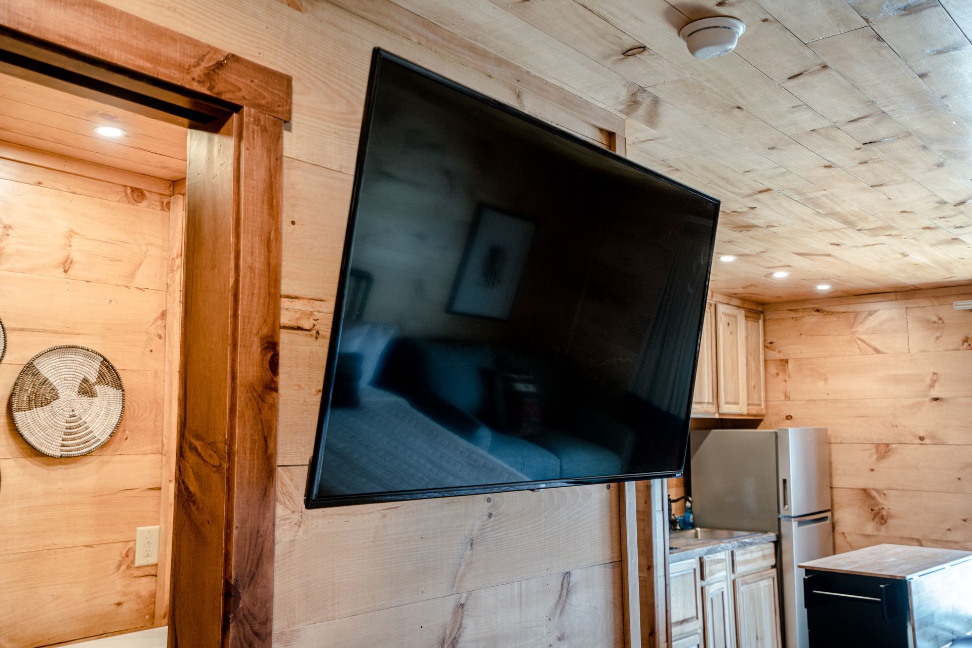 A flat screen tv is mounted on a wooden wall in a cabin.