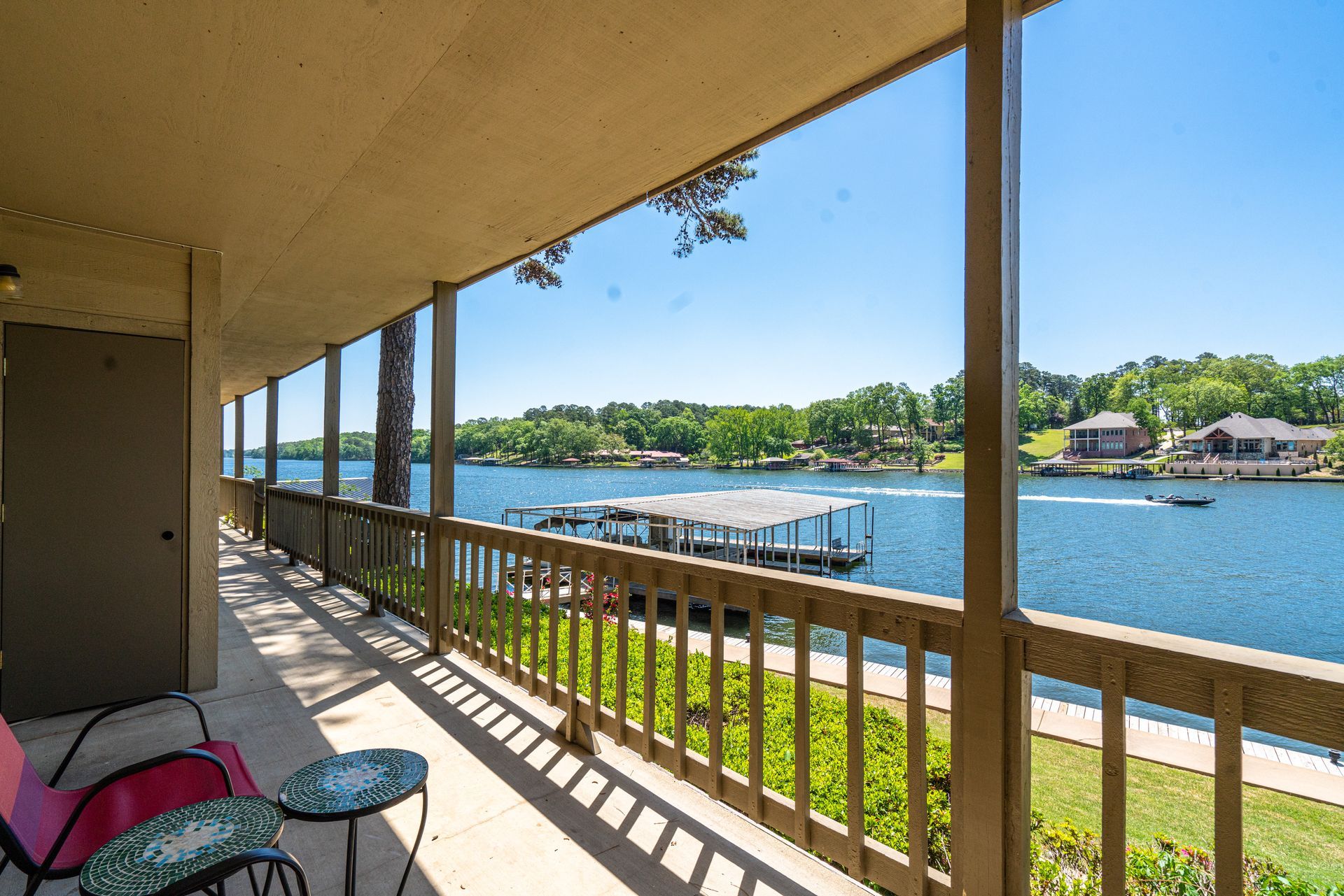 A balcony overlooking a lake with a boat docked in the water.