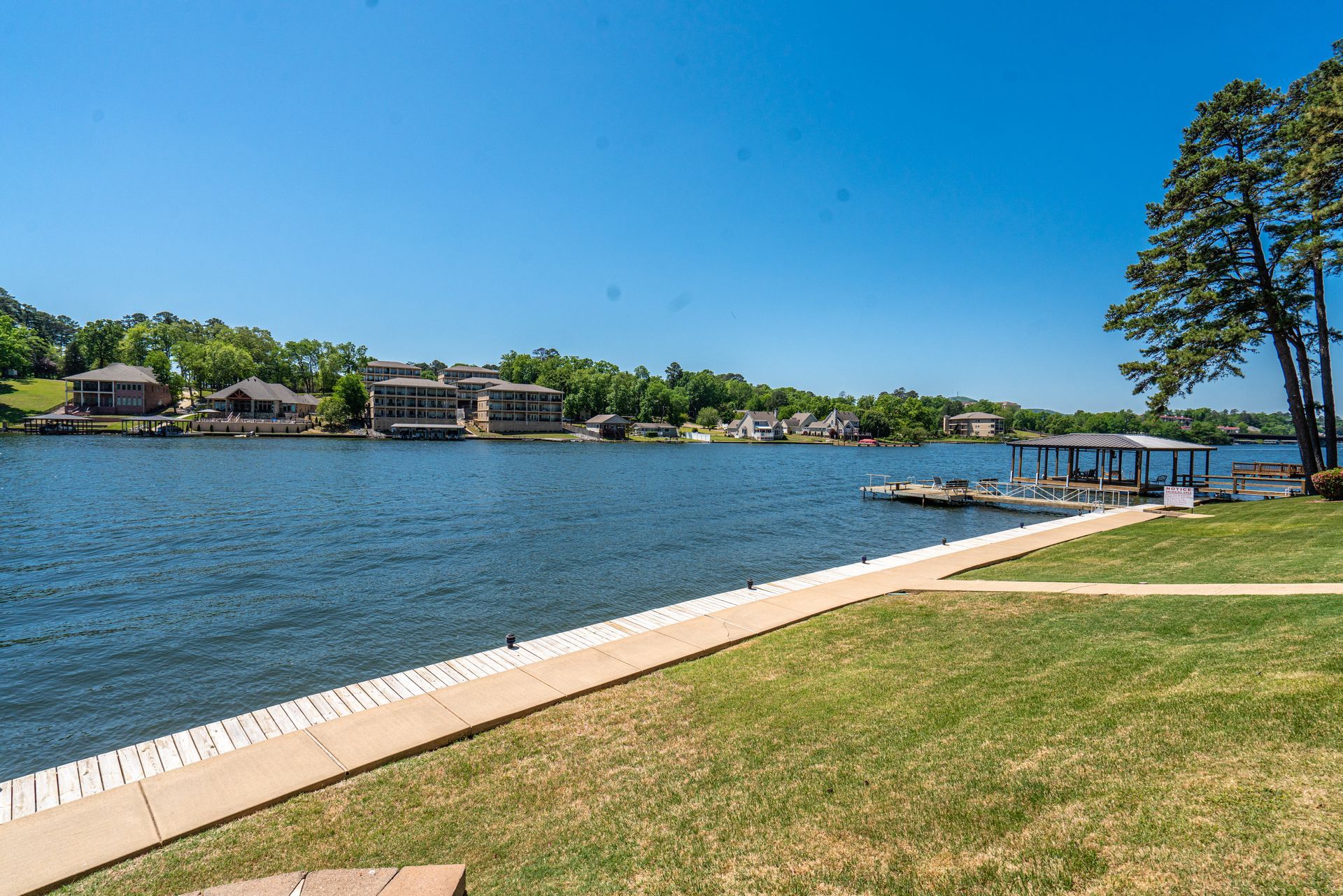 A large body of water surrounded by trees and houses on a sunny day.