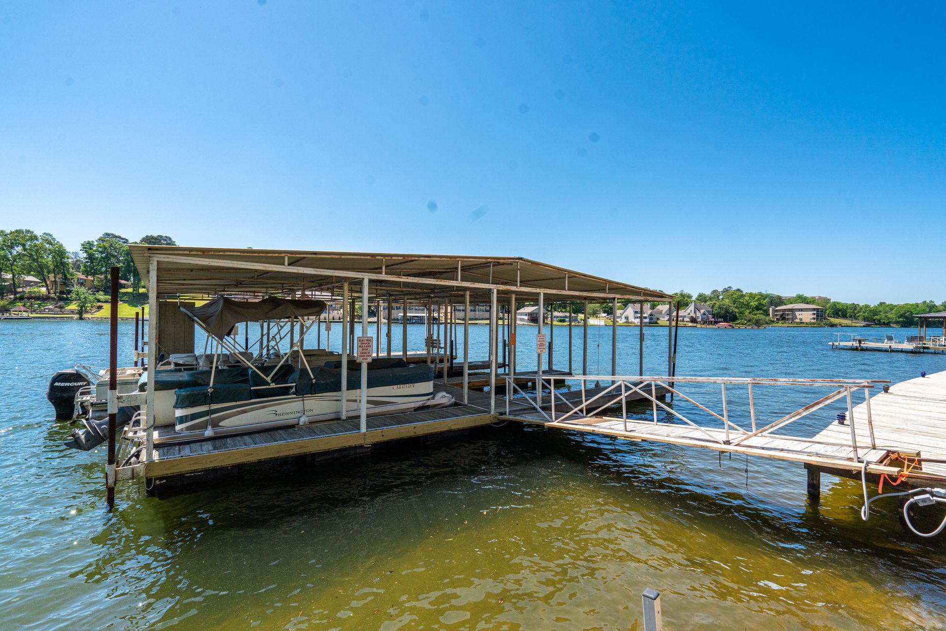 A boat is docked at a dock on a lake on a sunny day.