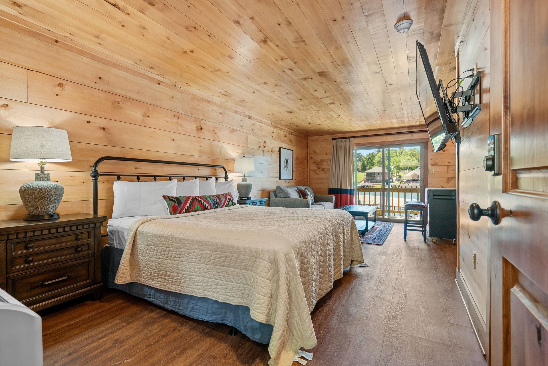 A bedroom in a log cabin with a king size bed and a flat screen tv.