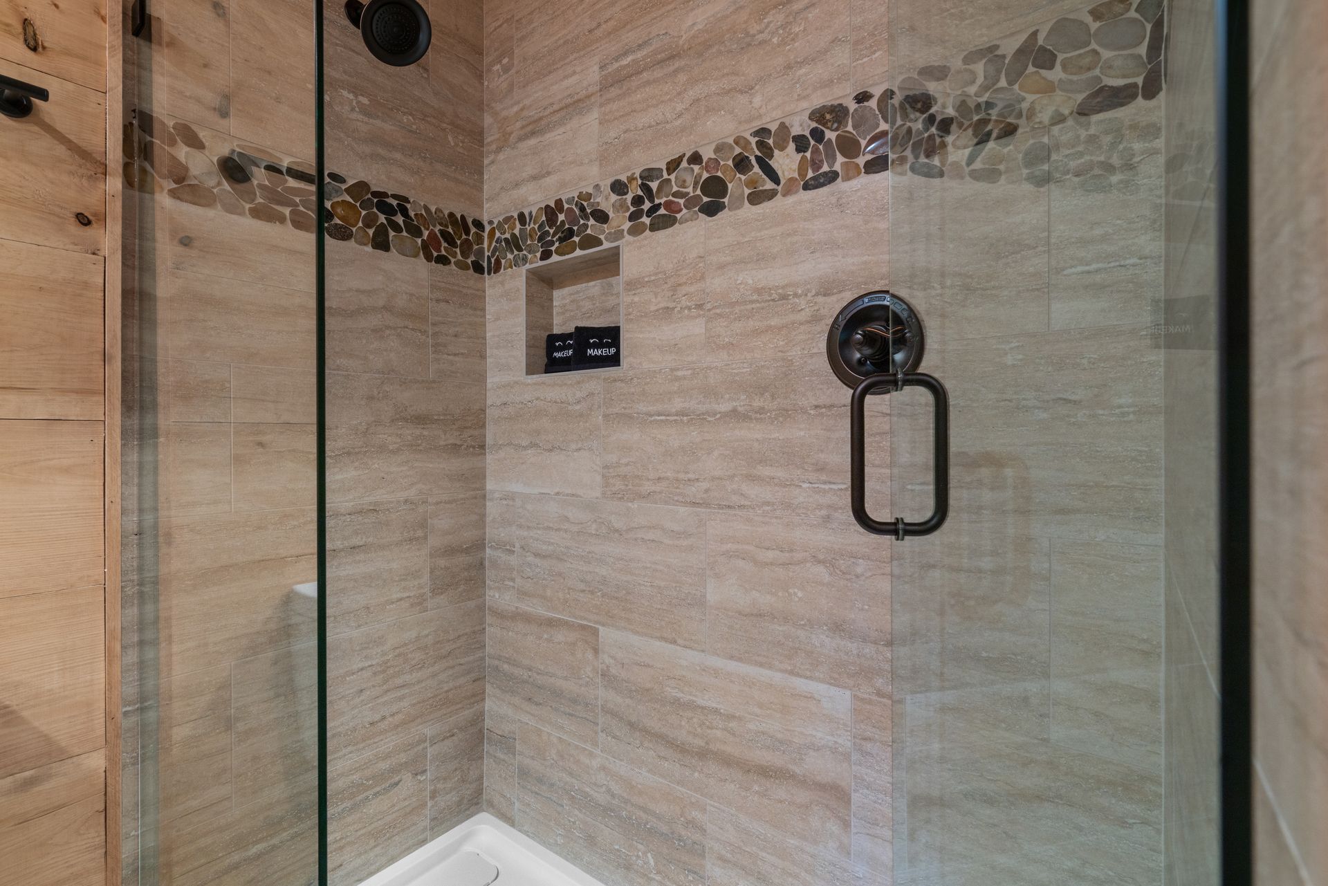 A bathroom with a walk in shower with a glass door.