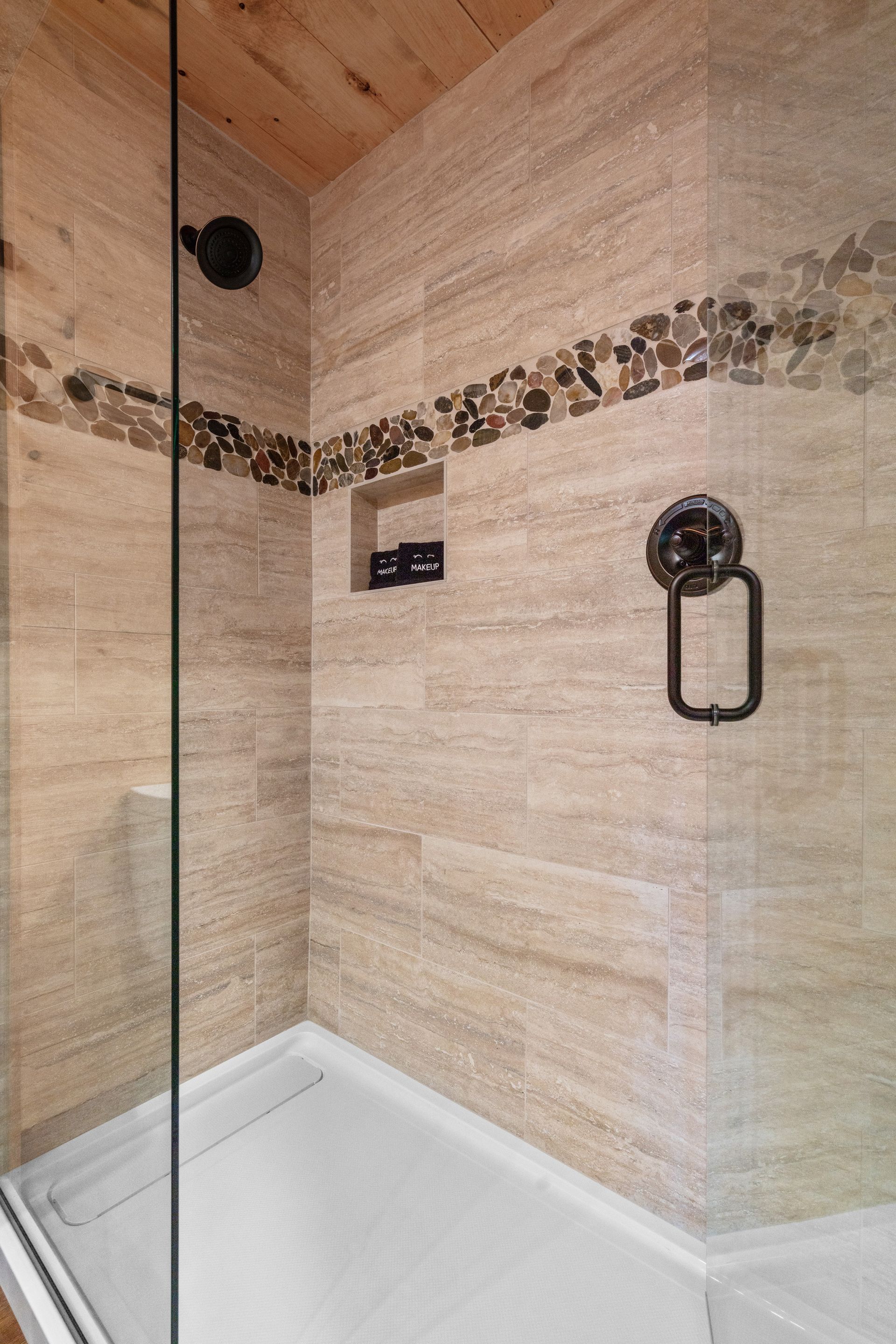 A bathroom with a walk in shower and a glass door.