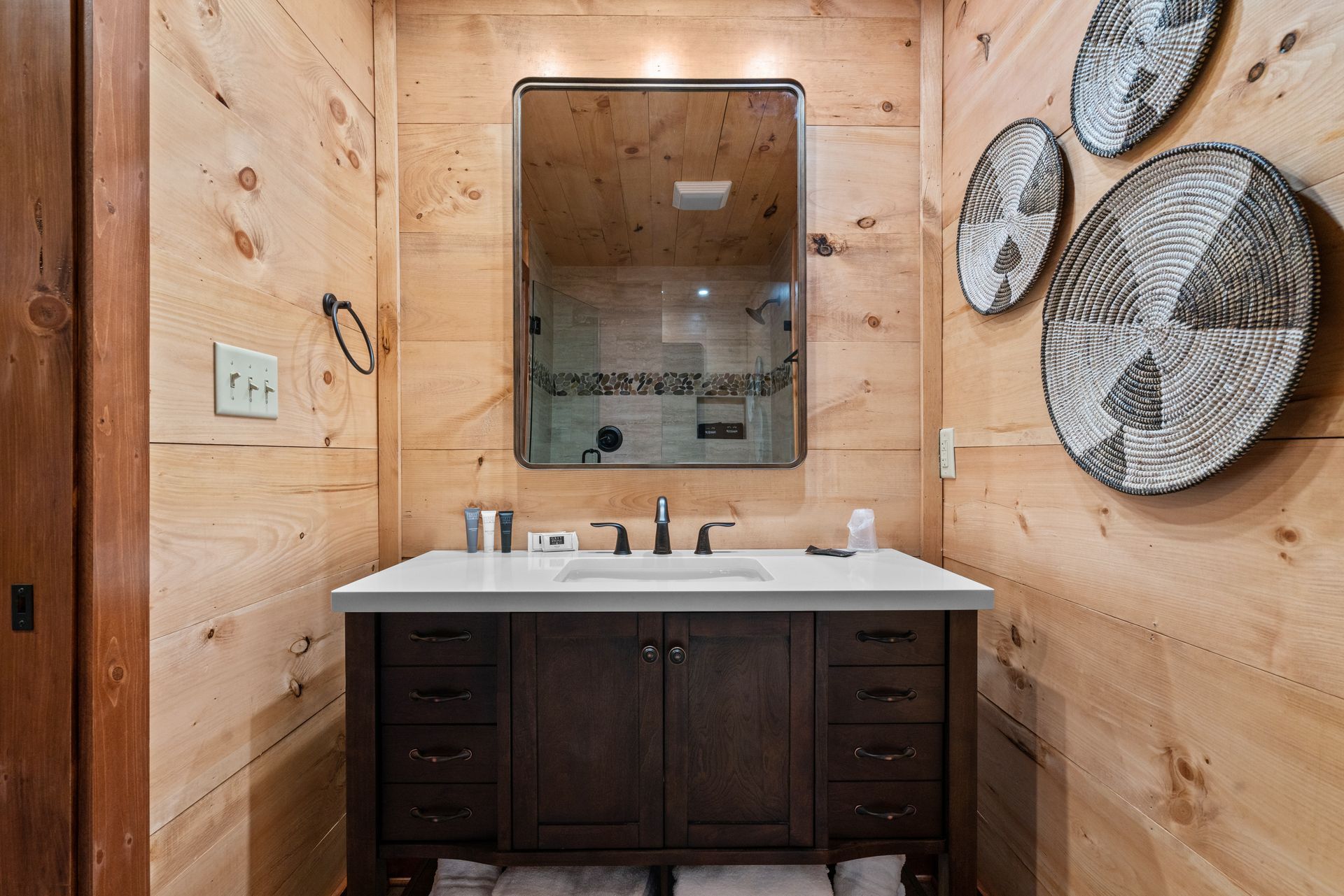 A bathroom with a sink , mirror and wooden walls.