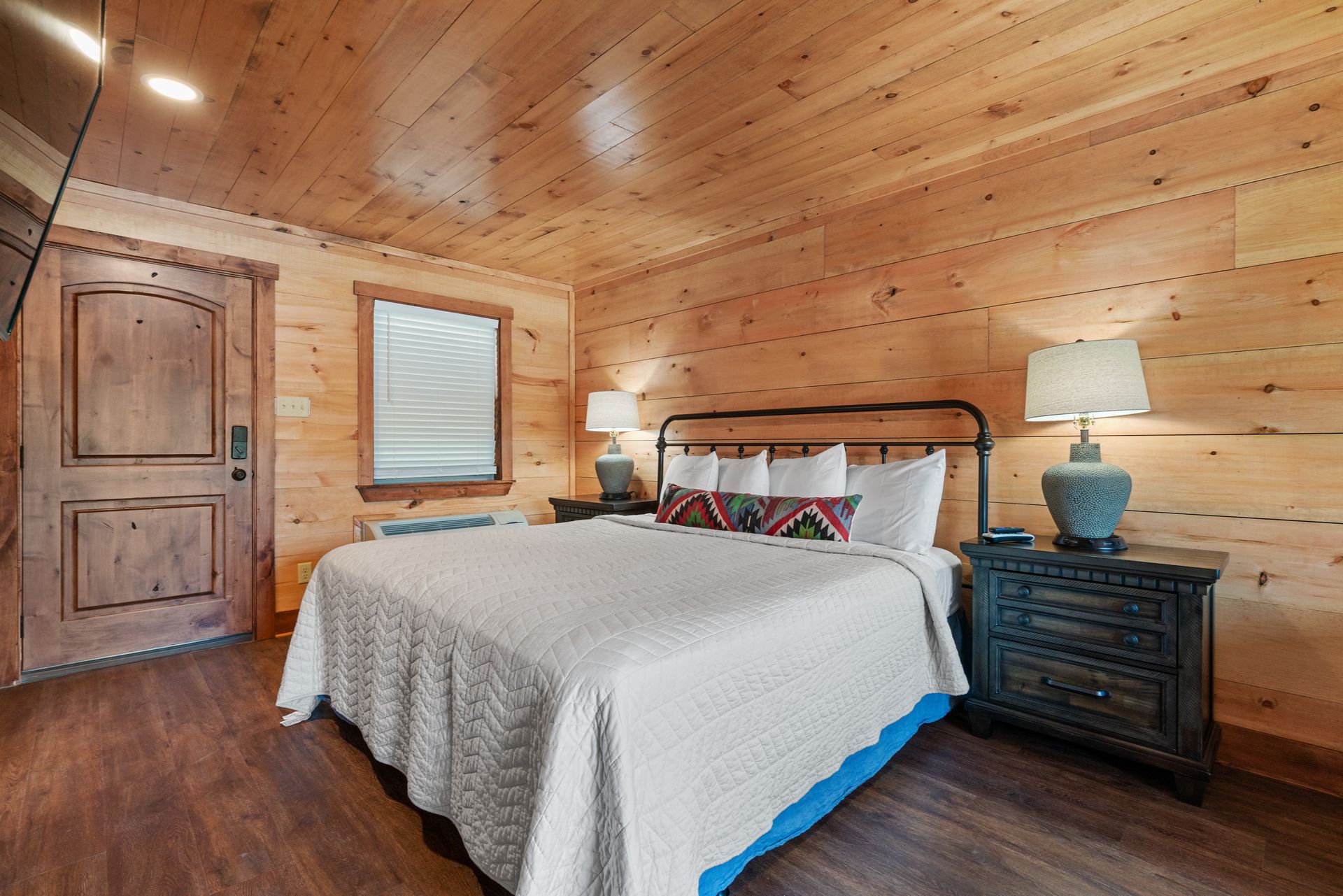 A bedroom in a log cabin with a king size bed , two nightstands , and a television.