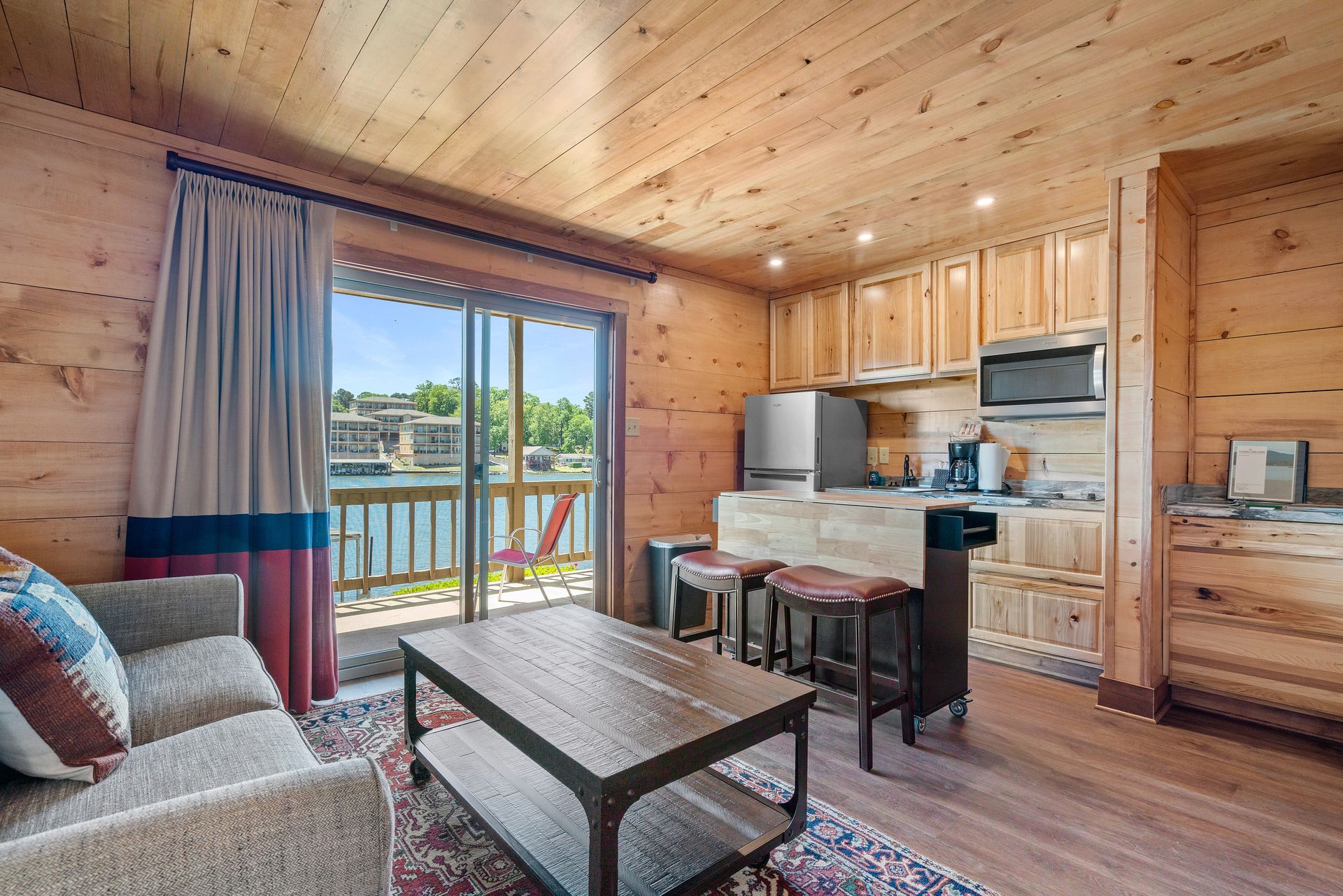 A living room with a couch , coffee table , and kitchen in a cabin.