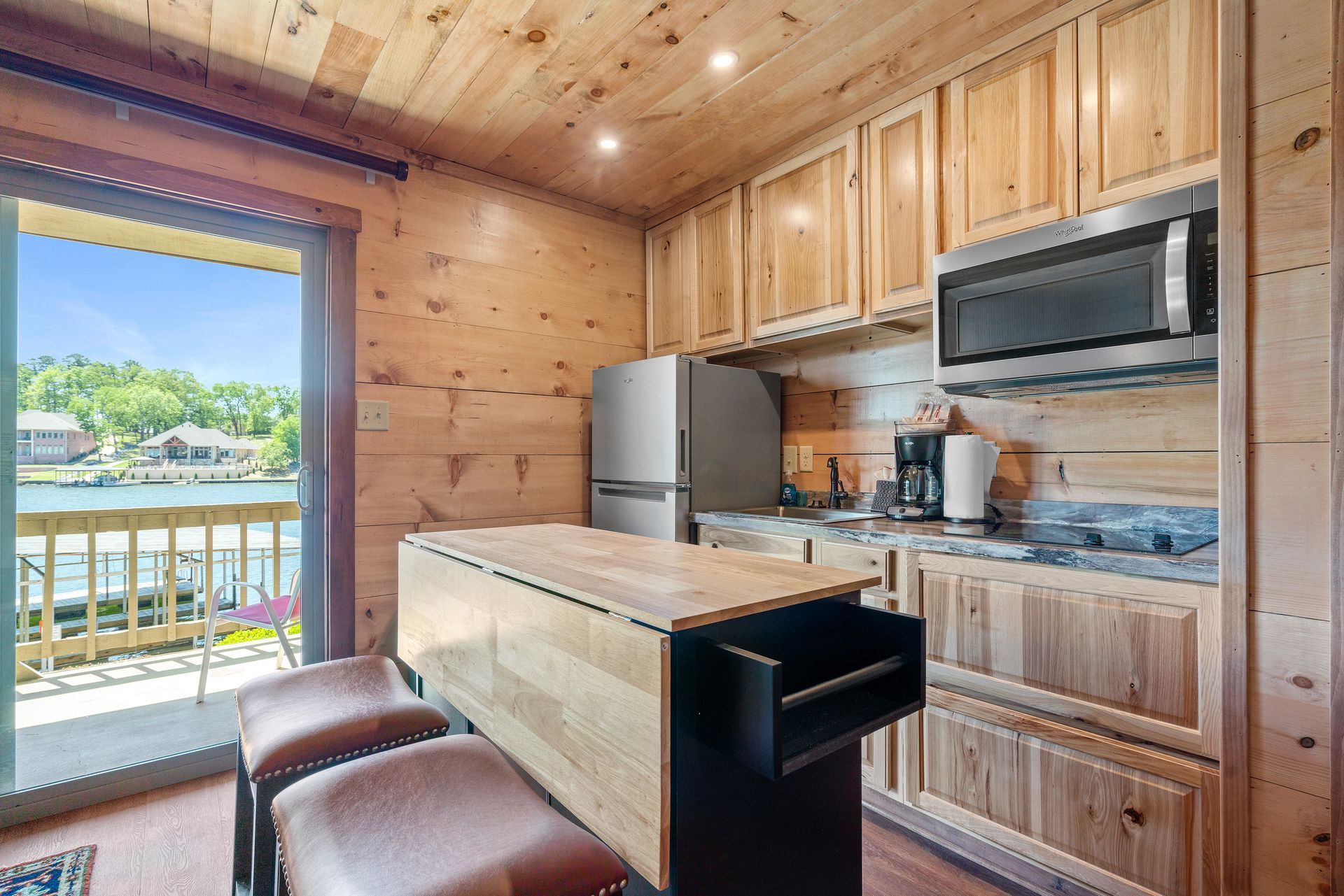 A kitchen with wooden cabinets , stainless steel appliances , a refrigerator and a microwave.