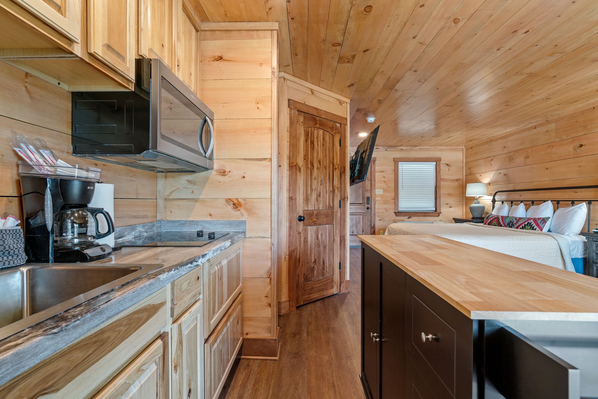 A kitchen in a log cabin with a sink , microwave , and coffee maker.