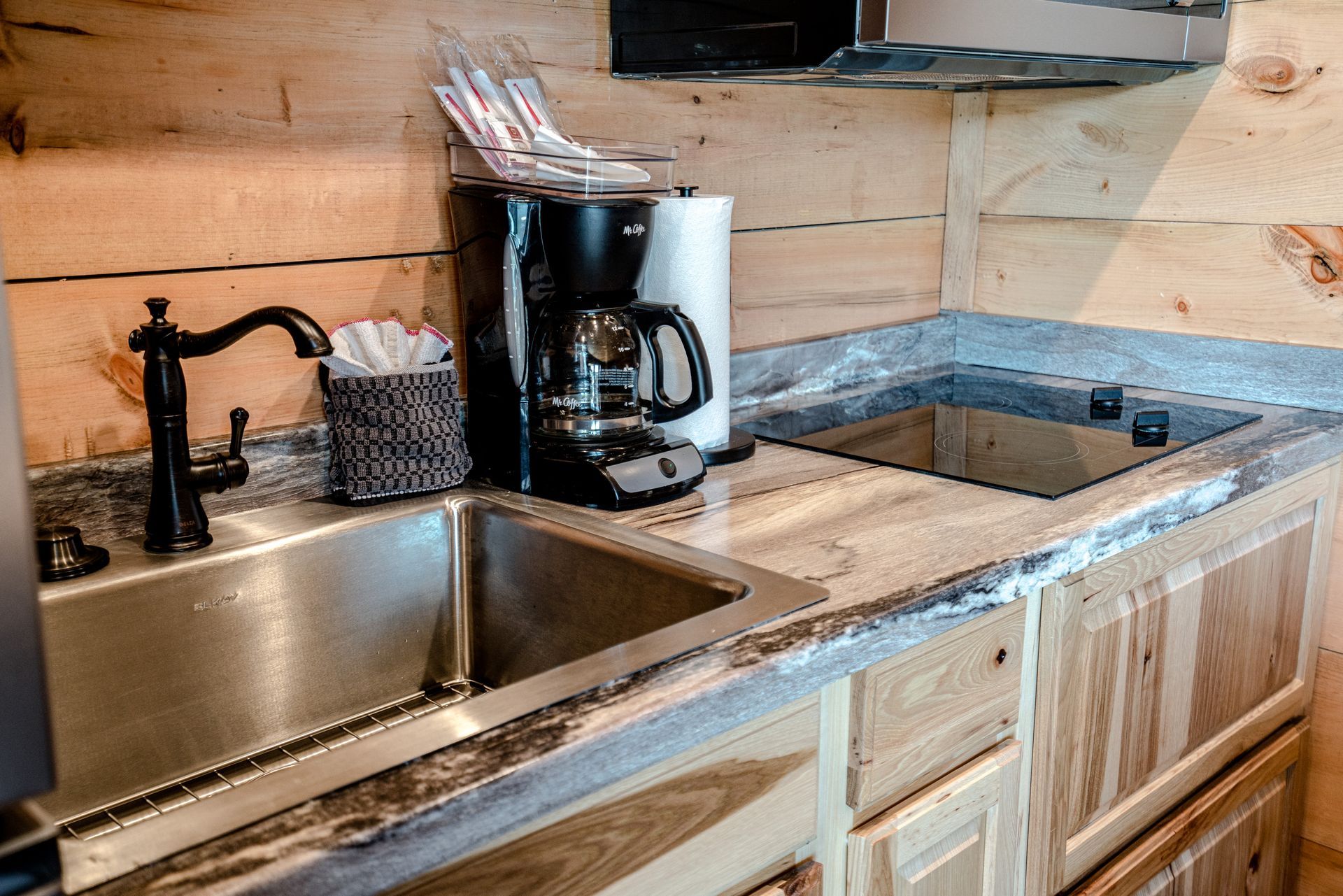 A kitchen with a sink , stove and coffee maker.