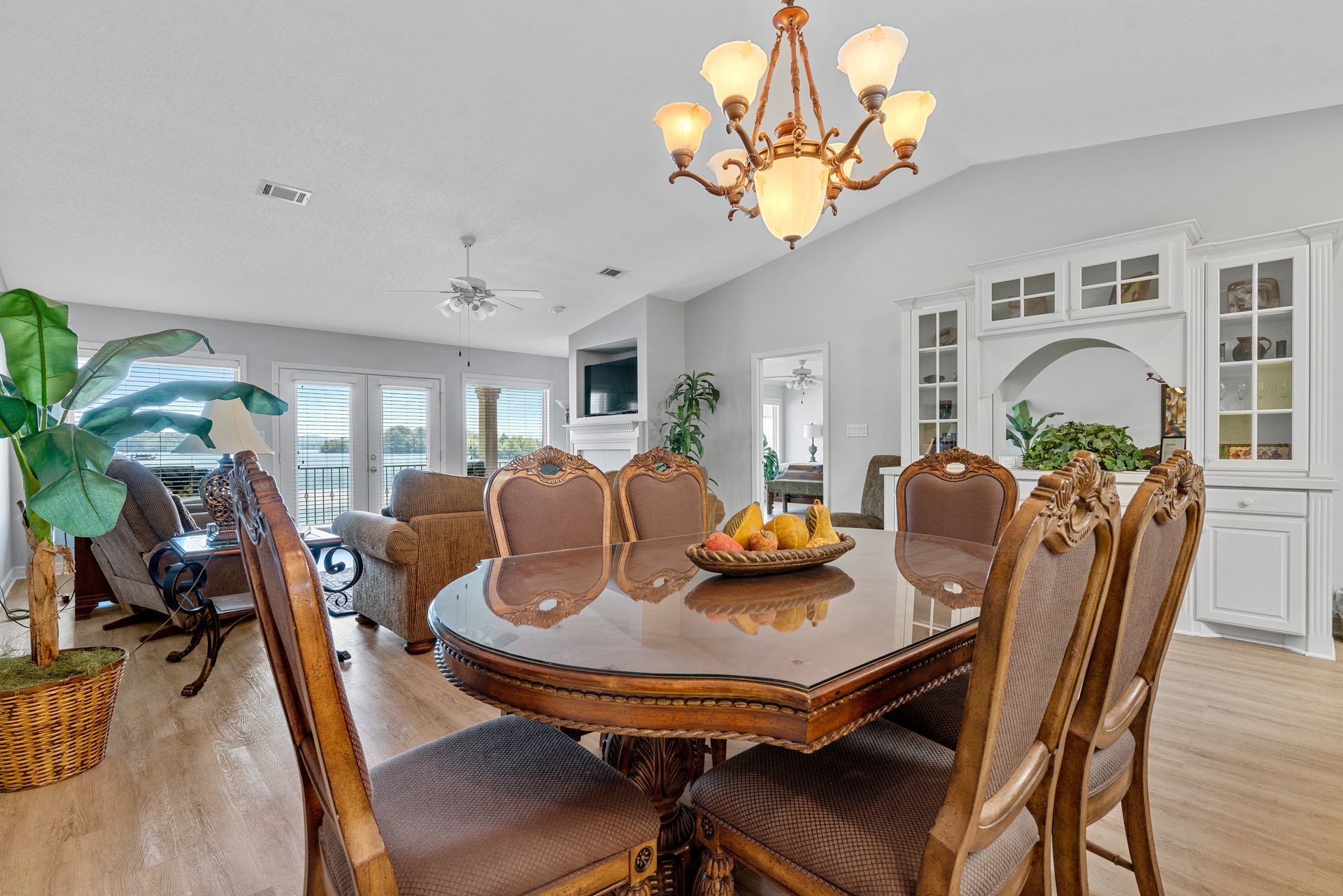 A dining room table and chairs in a living room with a chandelier.