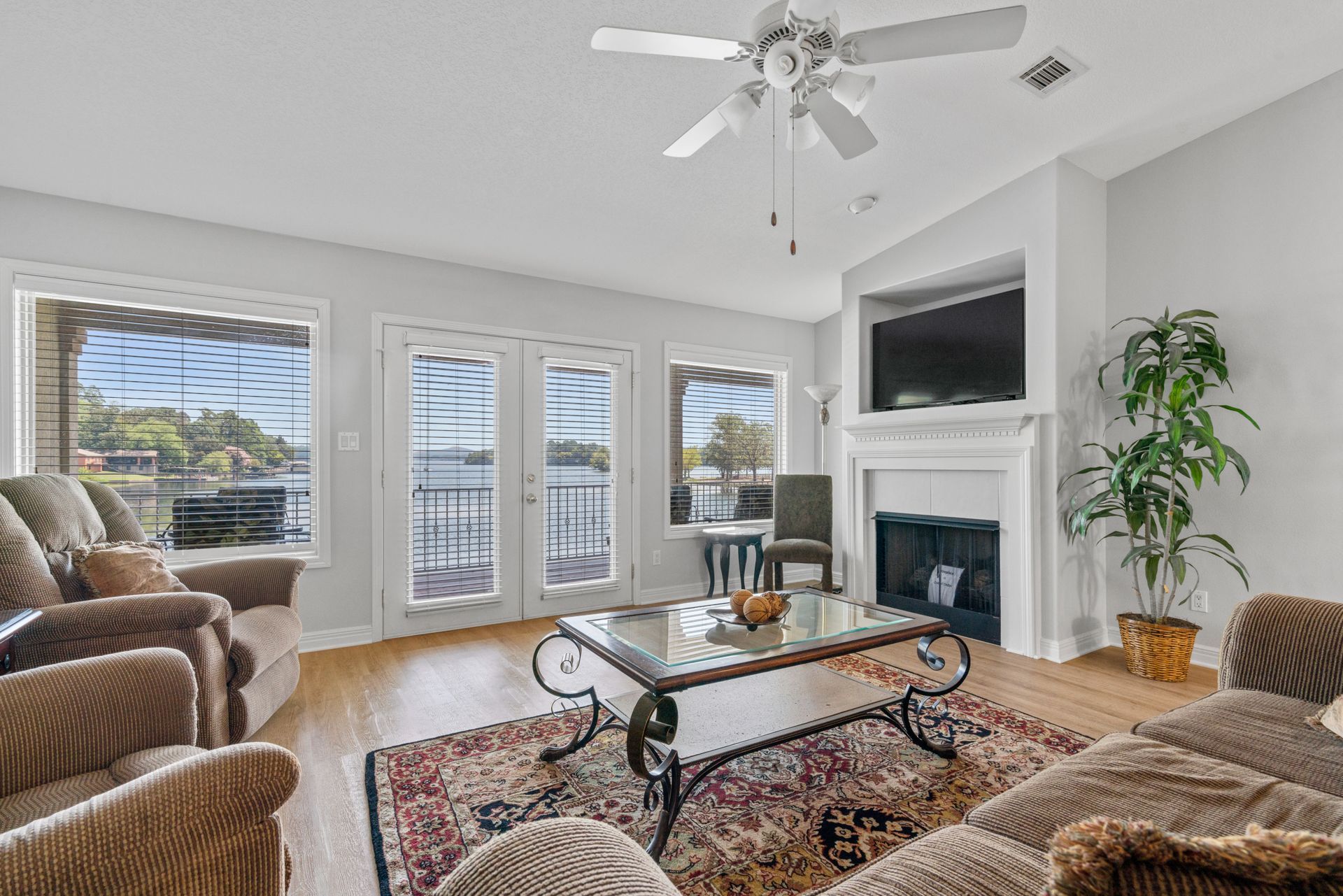 A living room with a couch , chairs , coffee table , fireplace and ceiling fan.