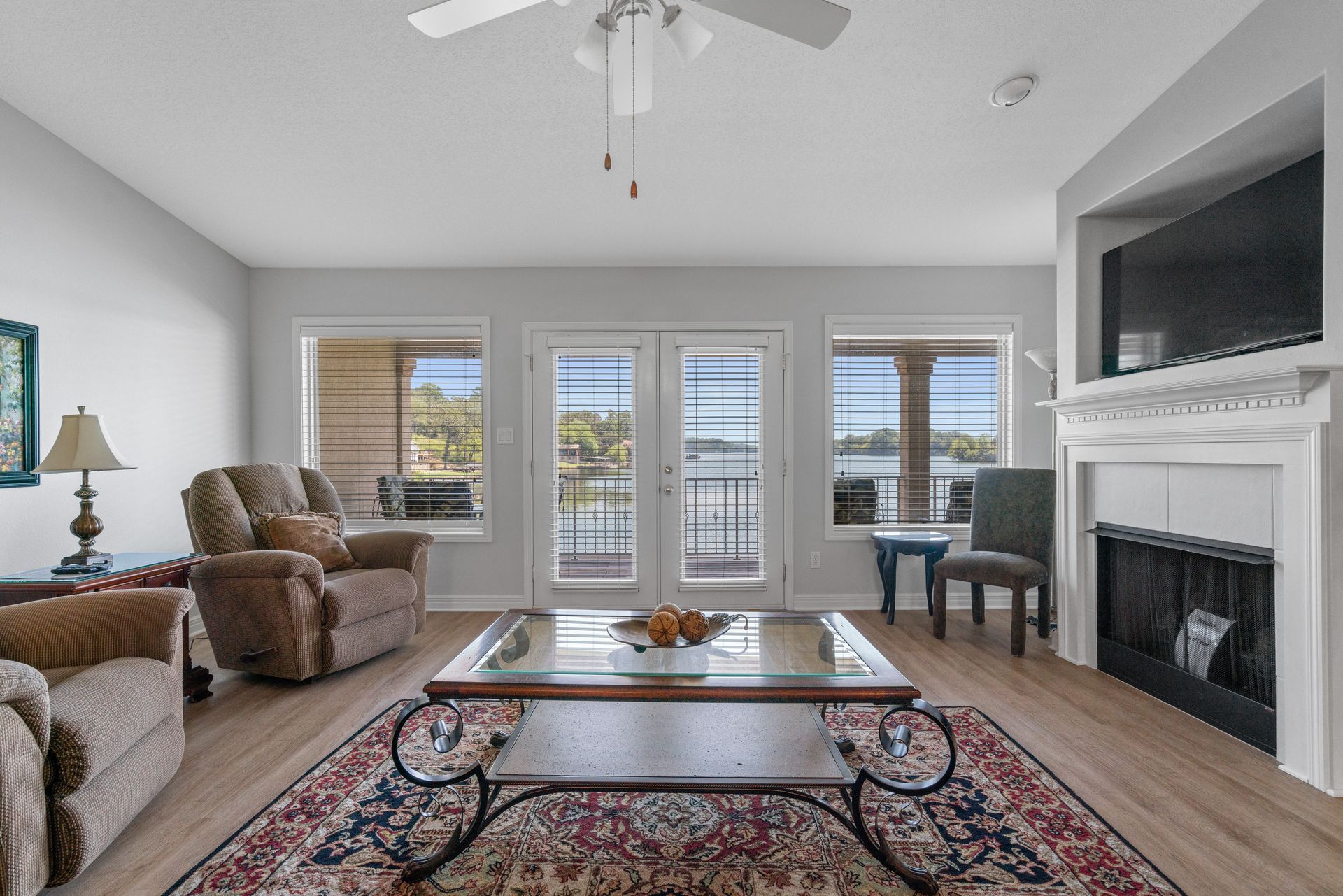 A living room with a fireplace , coffee table , chairs and a ceiling fan.
