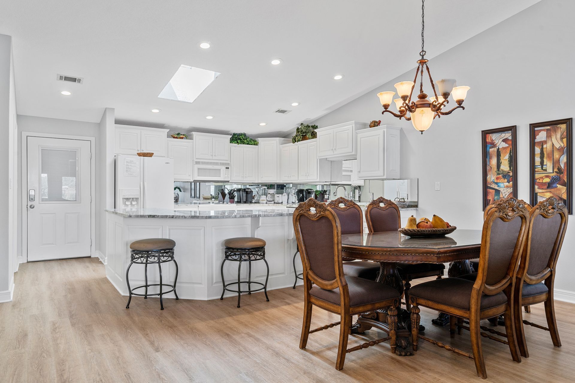 A dining room table and chairs in a kitchen with a chandelier.
