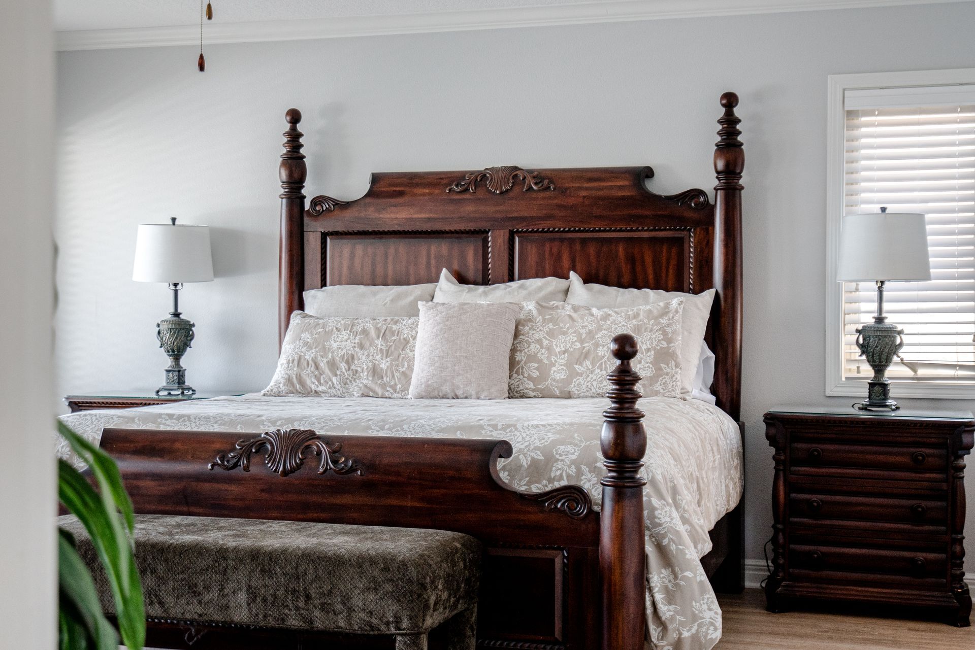 A bedroom with a king size bed , nightstands , lamps and a bench.