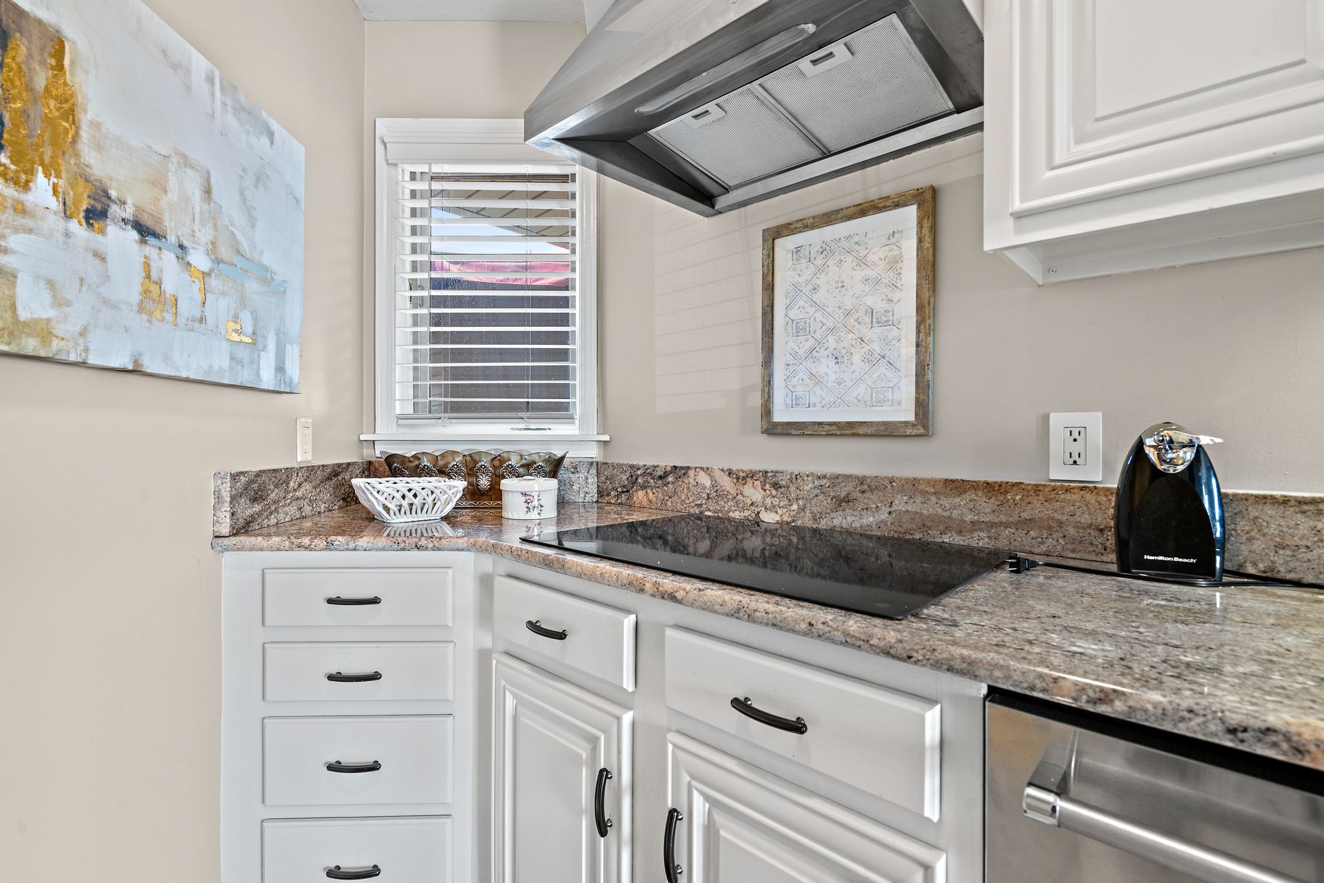 A kitchen with white cabinets , granite counter tops , stainless steel appliances and a stove top oven.