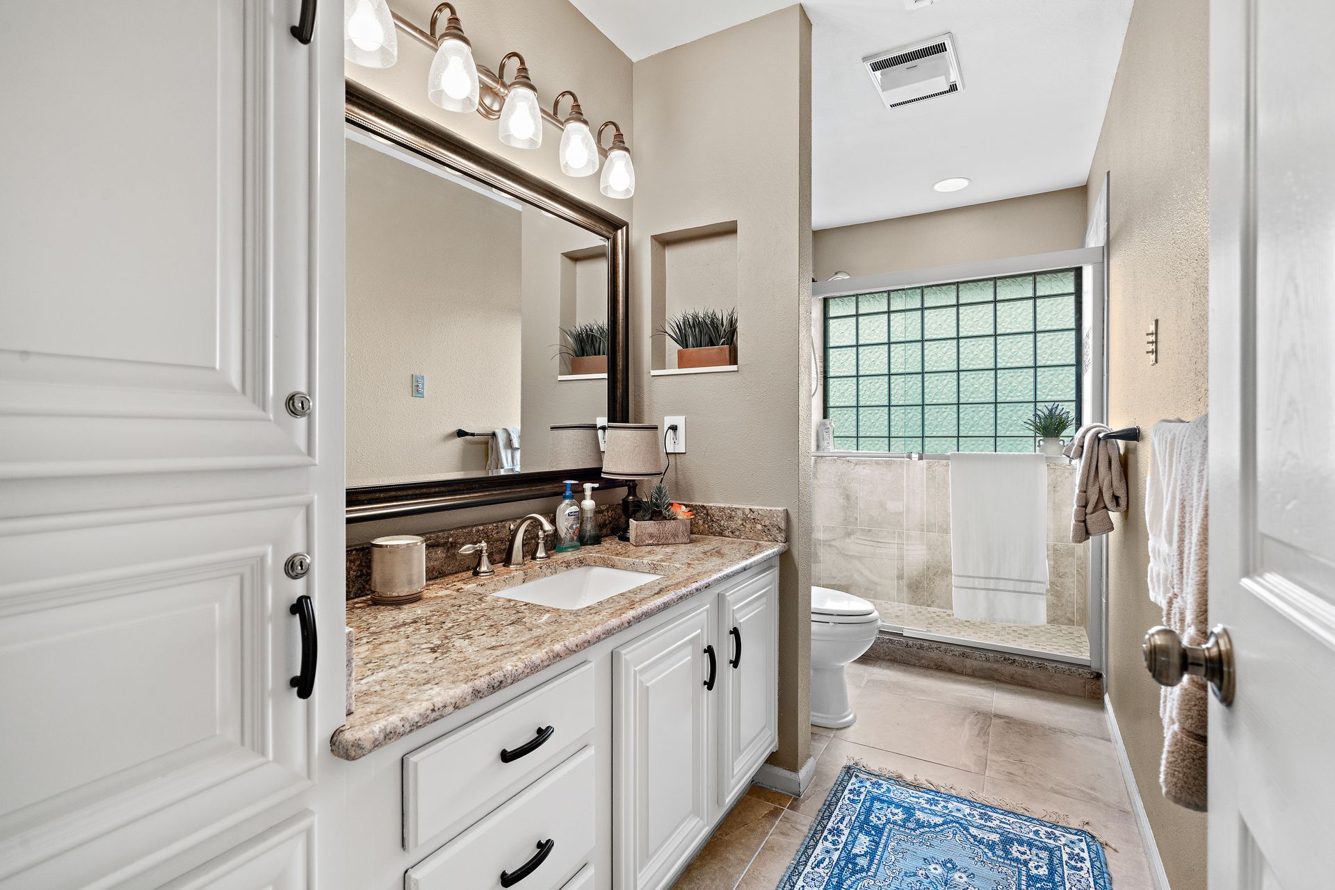 A bathroom with a sink , mirror , and walk in shower.