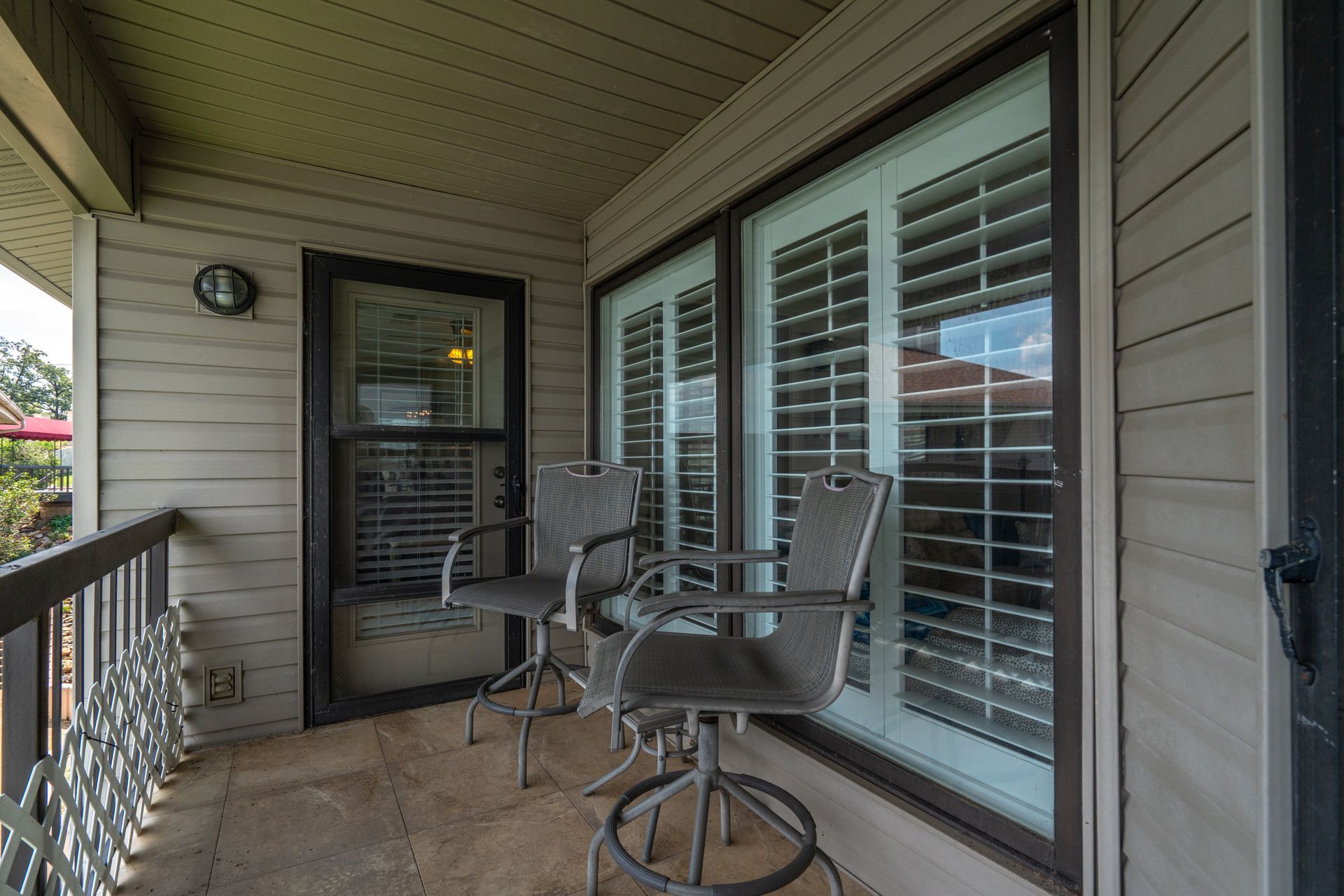 A balcony with two chairs and a table in front of a window.
