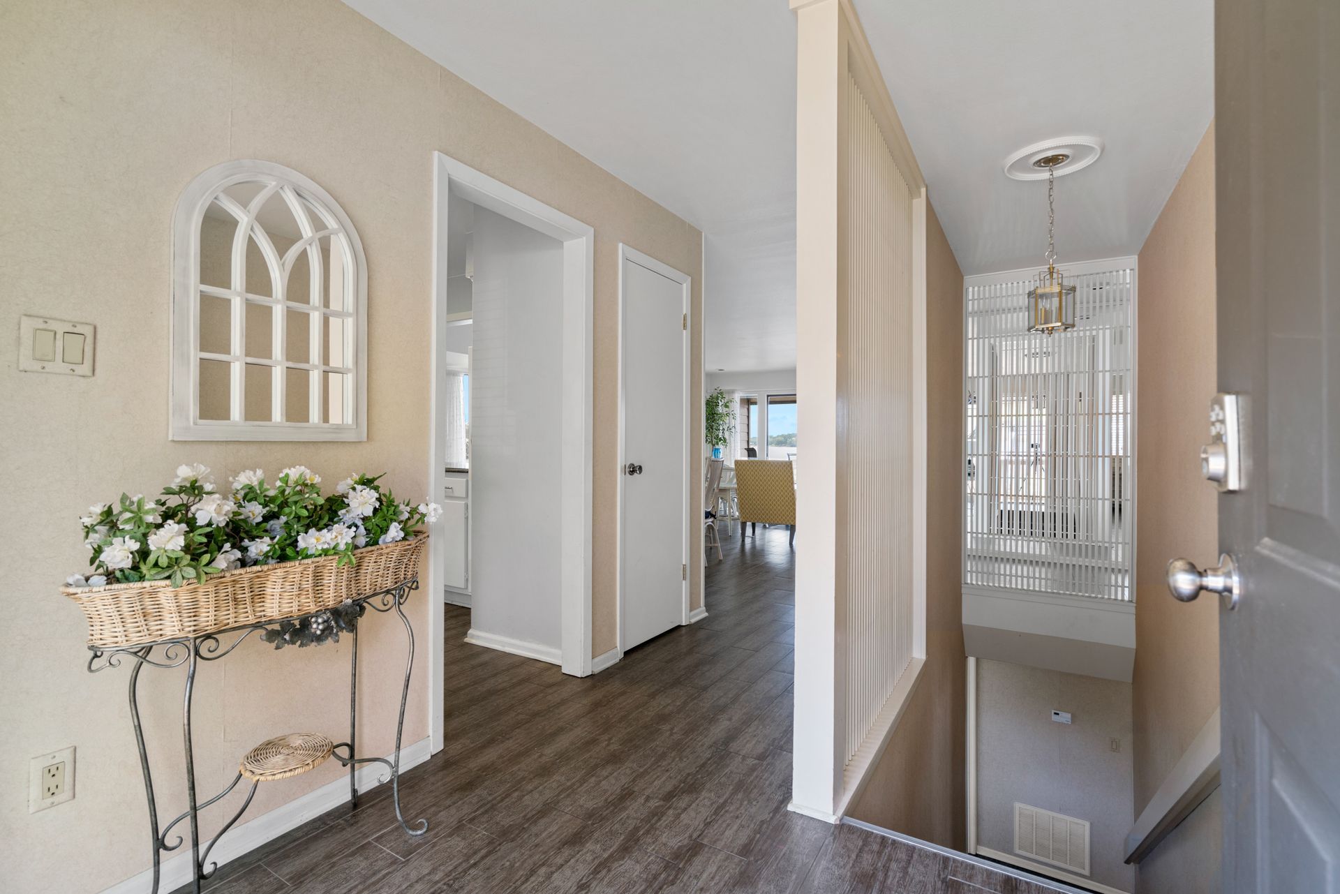 A hallway with a mirror on the wall and a table with flowers on it.