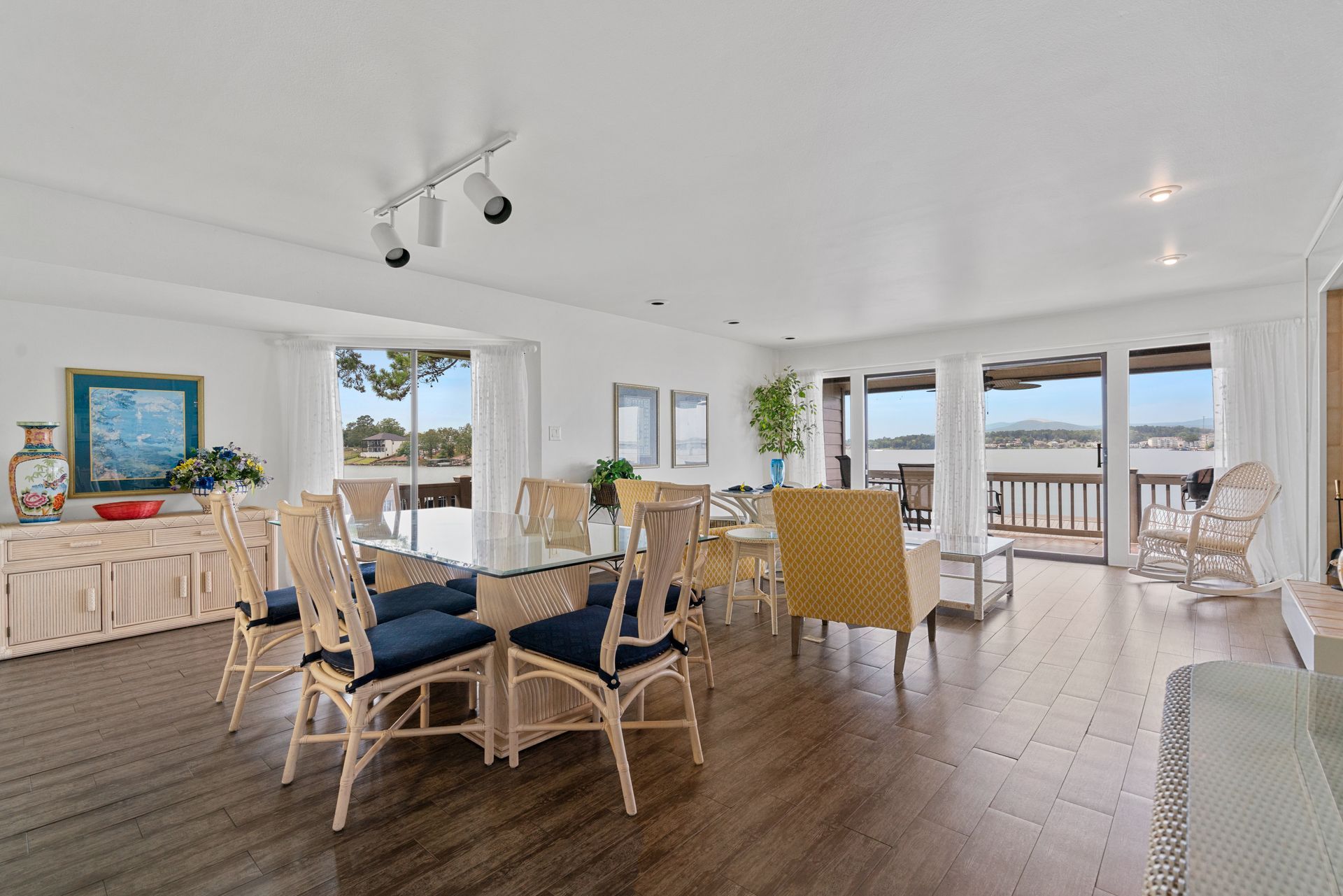 A living room with a dining table and chairs and a view of the ocean.