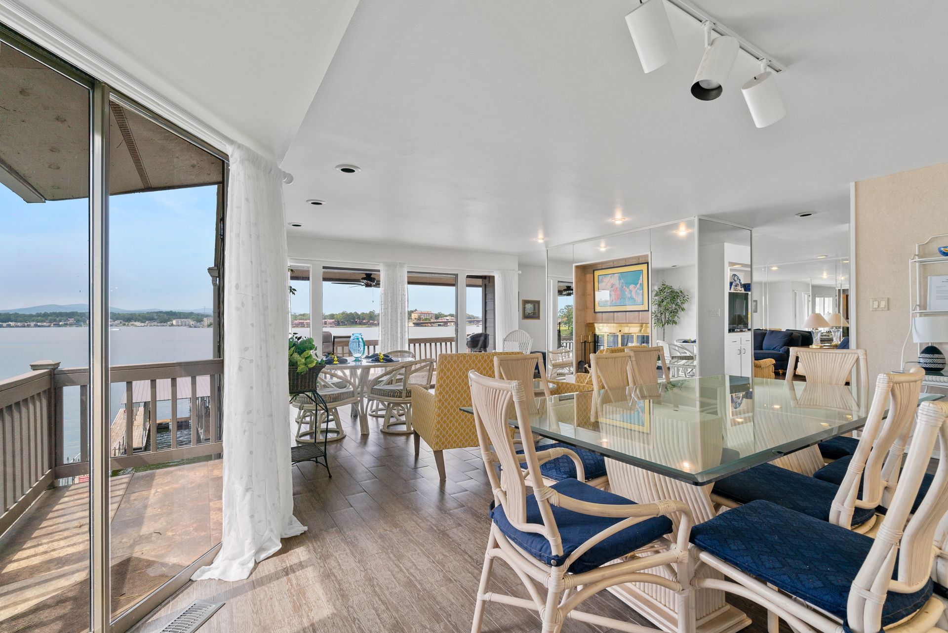 A dining room with a glass table and chairs and a view of the water.
