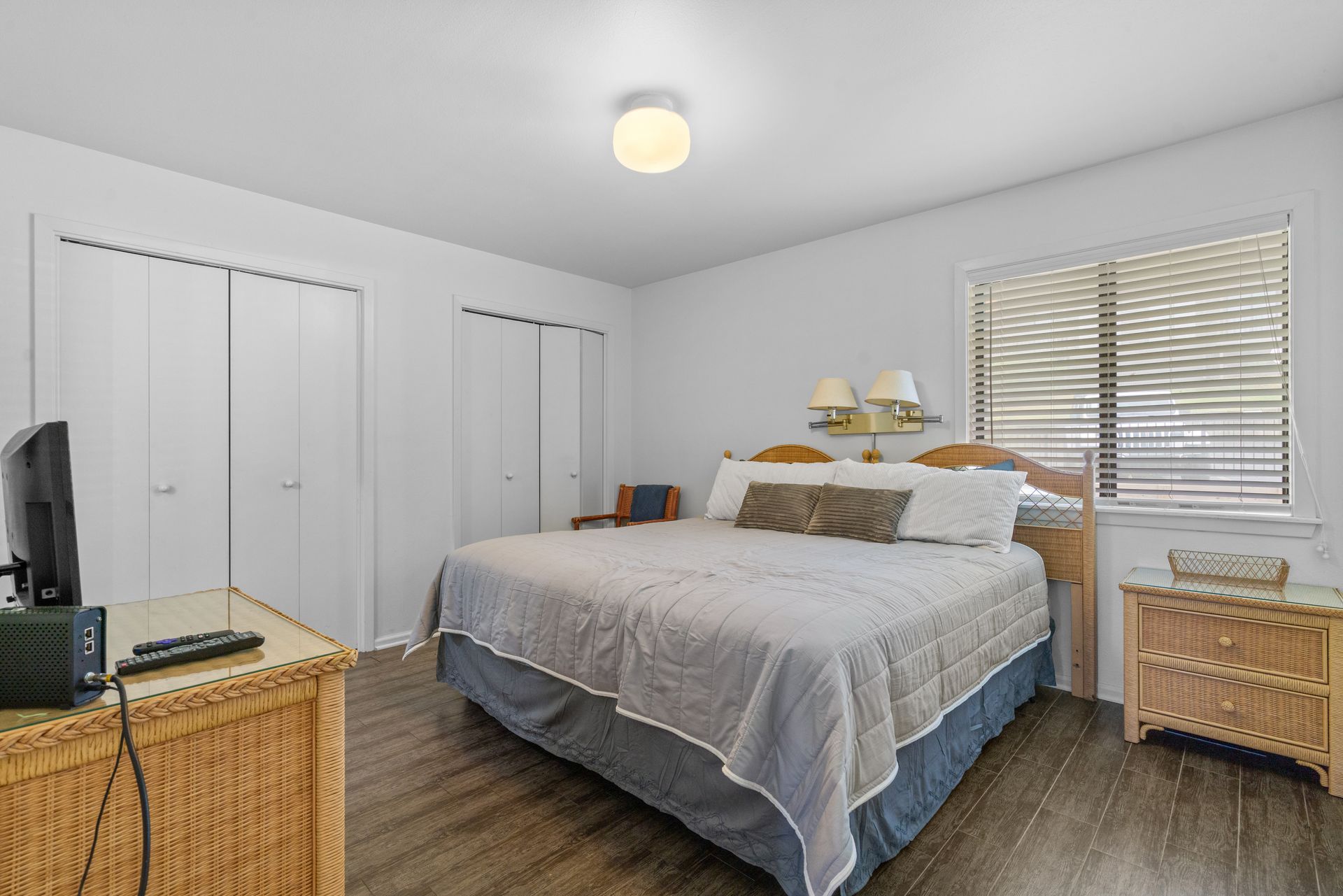 A bedroom with a king size bed , dresser , nightstand , and television.