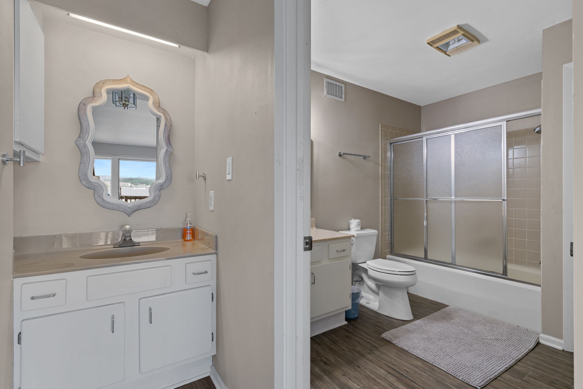 A bathroom with a sink , toilet , shower and mirror.