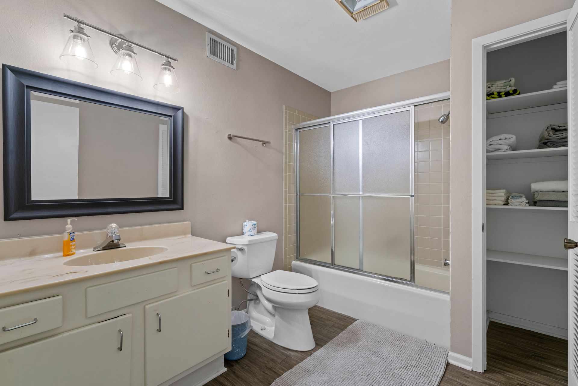 A bathroom with a toilet , sink , mirror and shower.