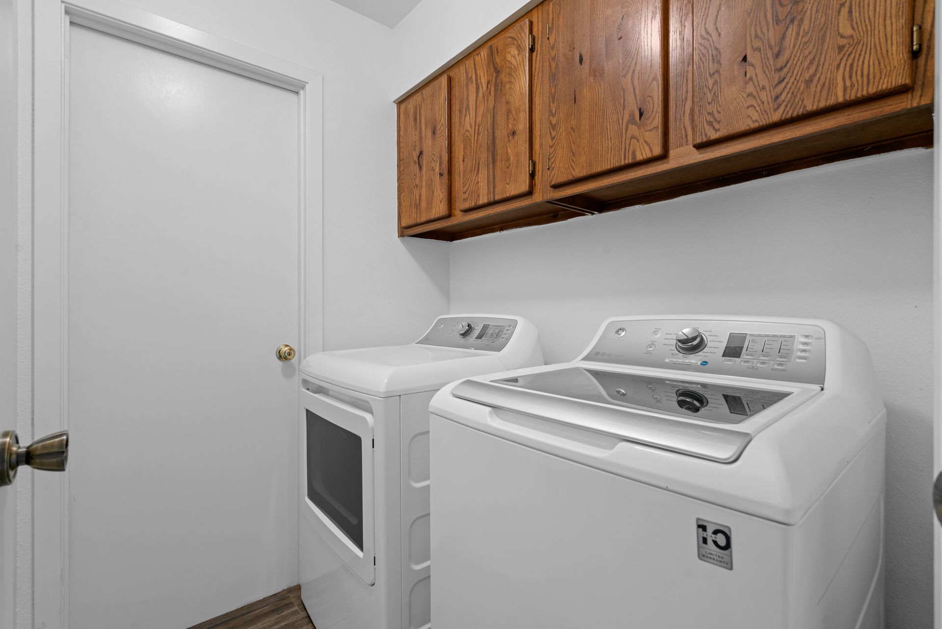 A laundry room with a washer and dryer and wooden cabinets.