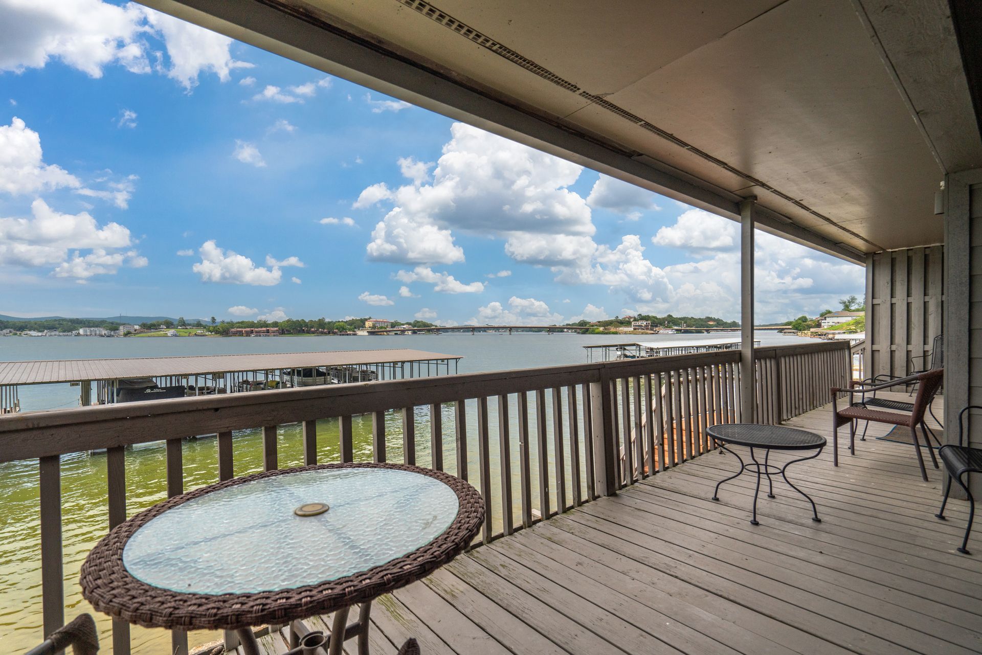 A large deck with a table and chairs overlooking a body of water.