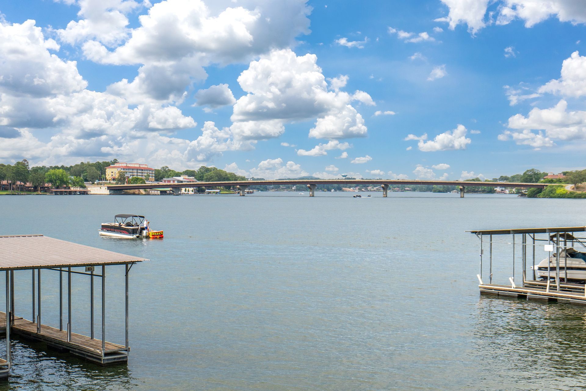 A boat is floating on a lake with a bridge in the background.