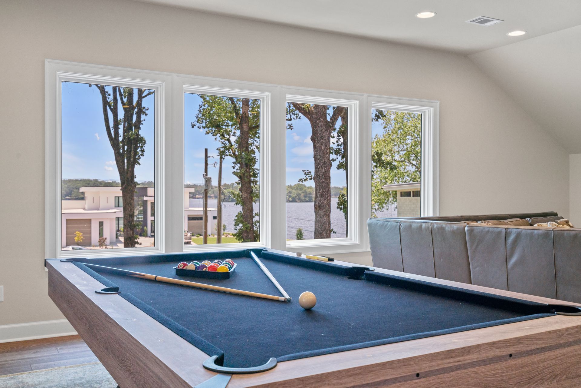 A pool table in a living room with a view of a lake