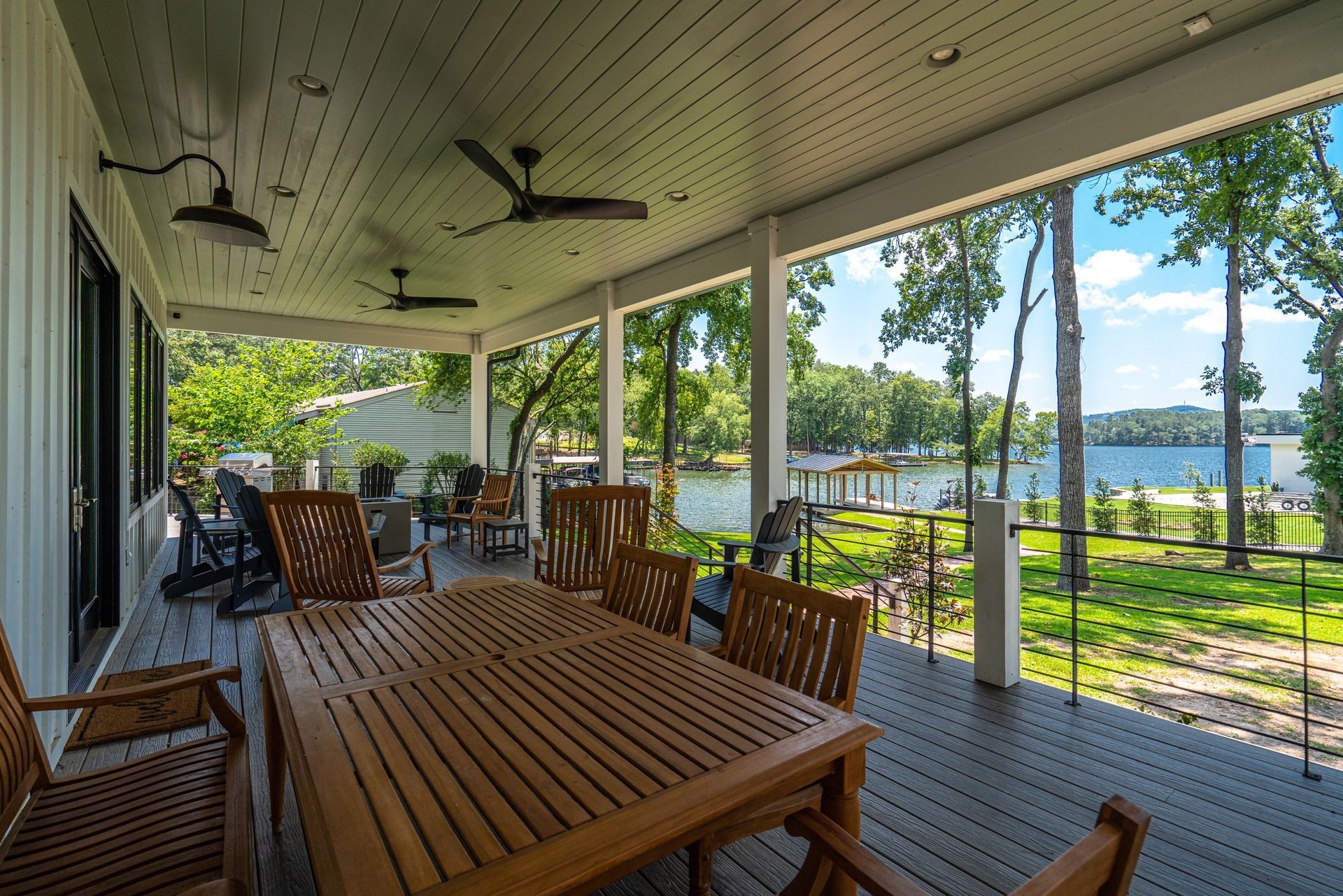 A porch with a table and chairs and a view of a lake.