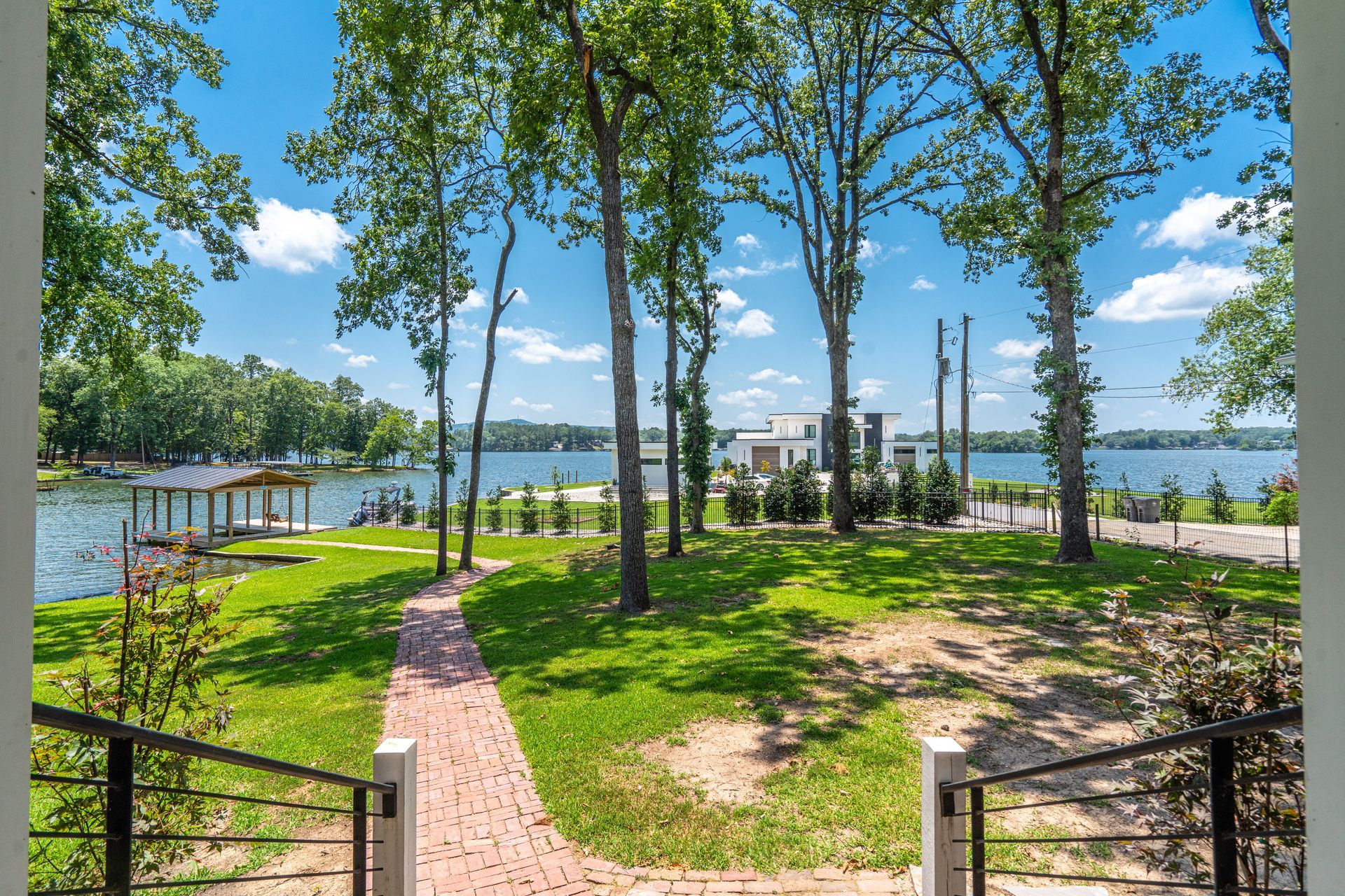 A brick walkway leading to a lake surrounded by trees and grass.
