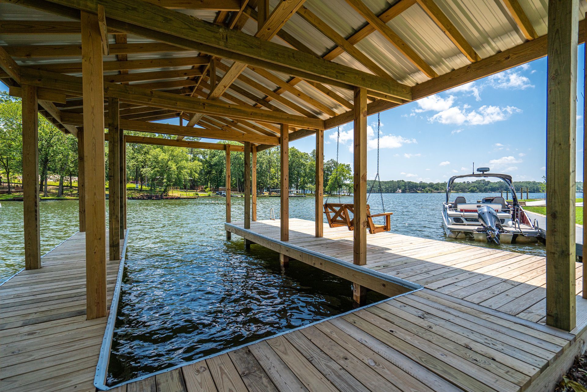 A boat is docked under a wooden dock on a lake.