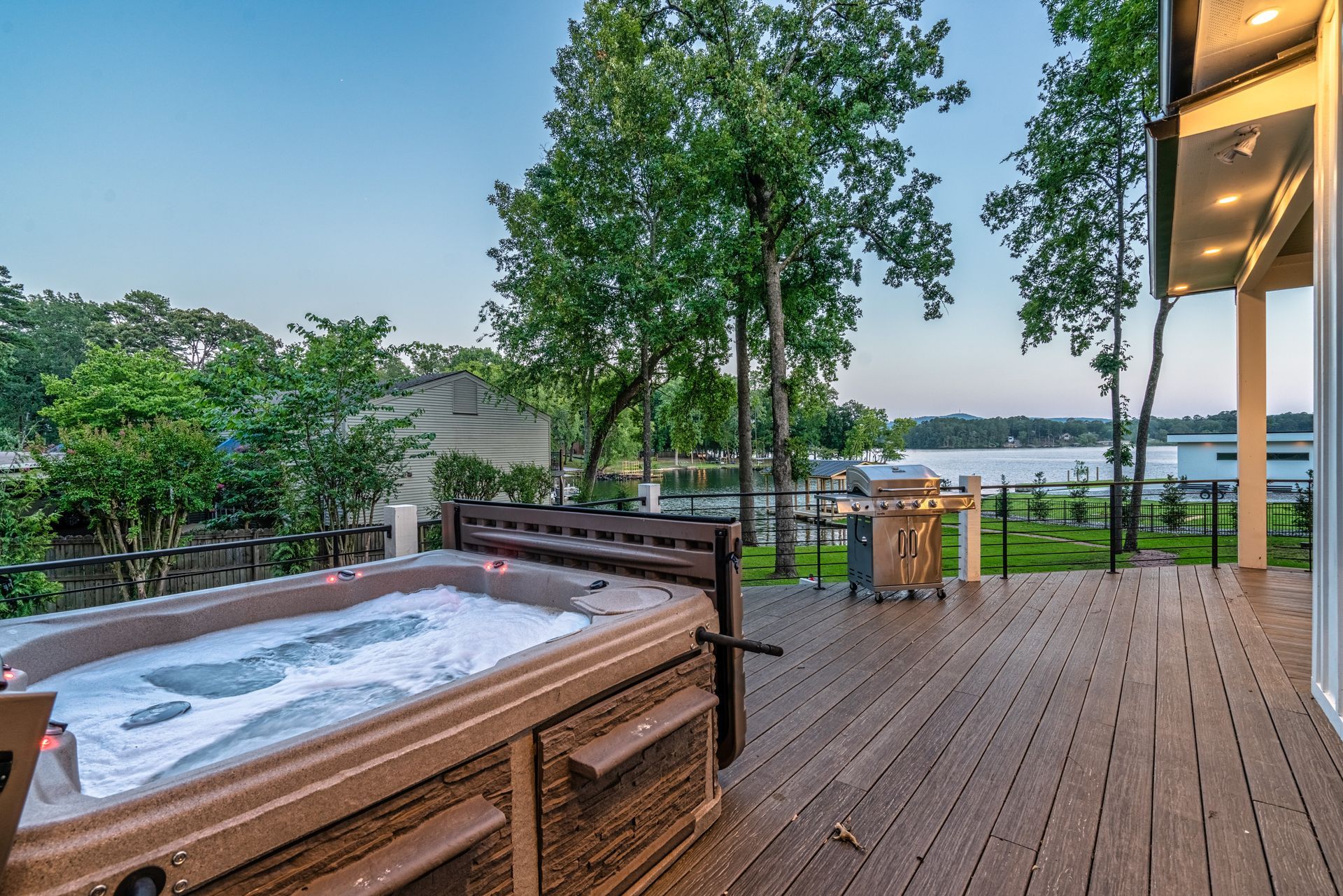 A hot tub is sitting on a wooden deck overlooking a lake.