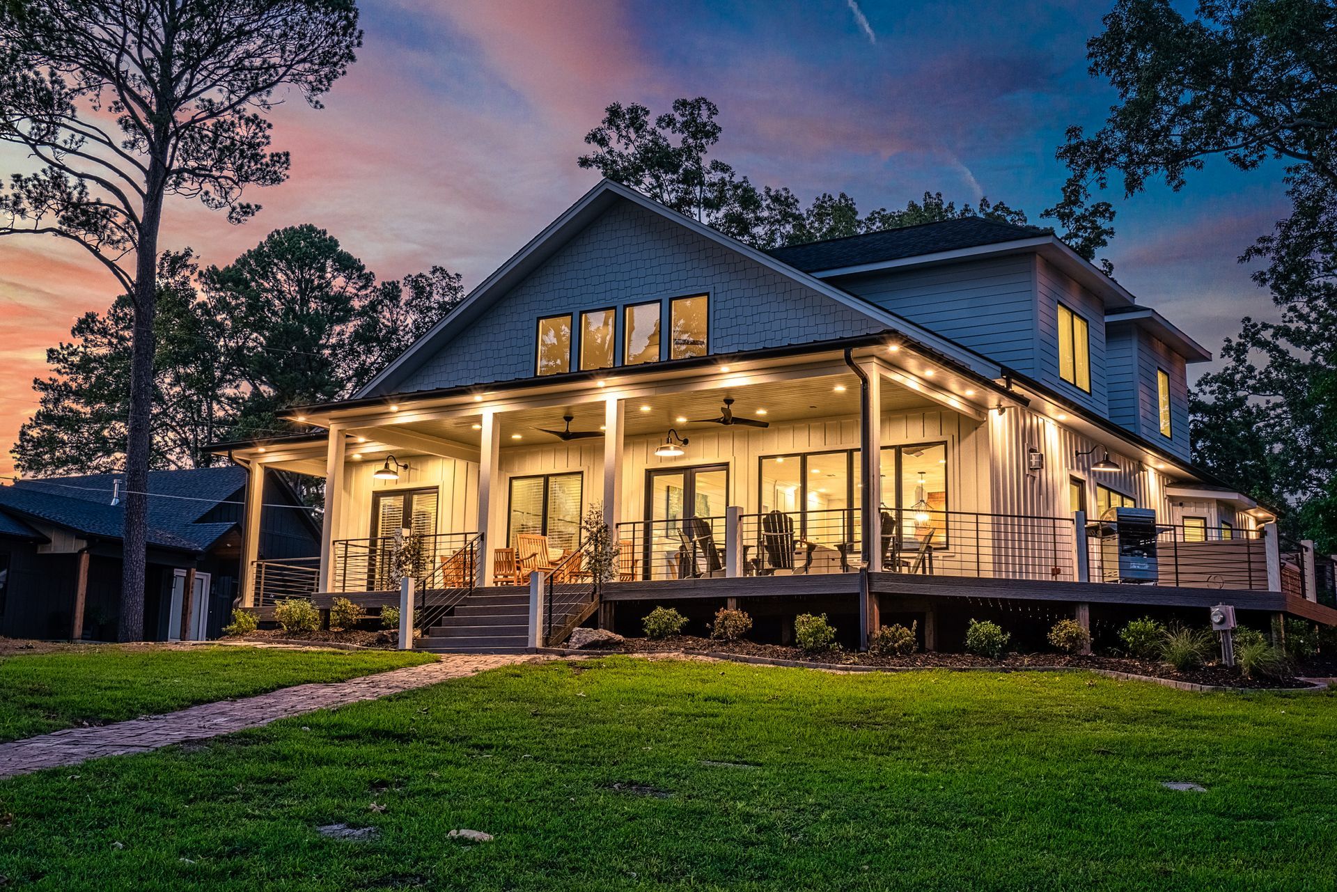 A large house with a large porch is lit up at night.