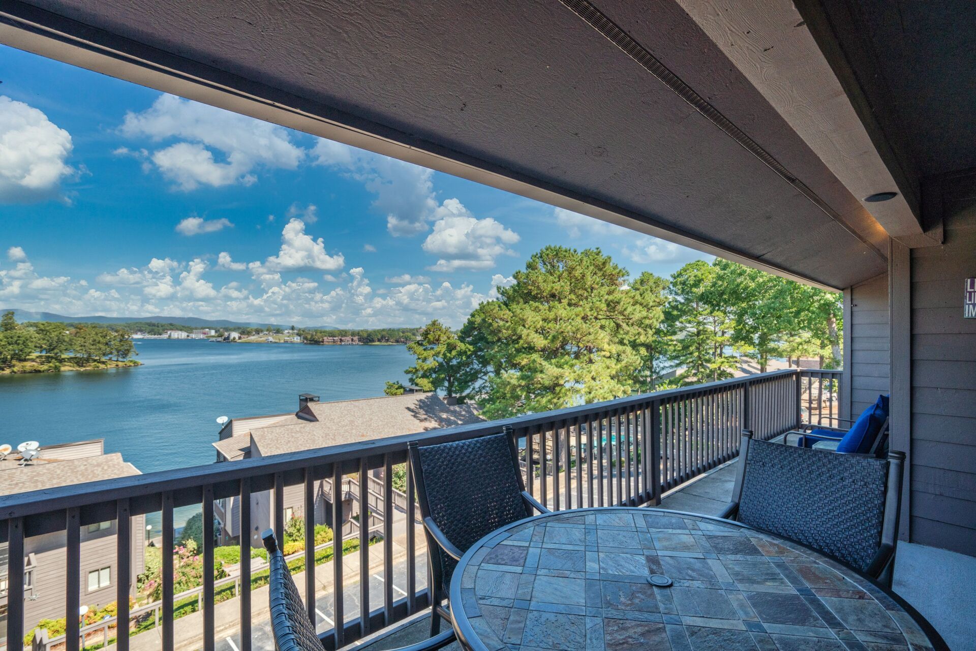 A balcony with a table and chairs overlooking a lake.
