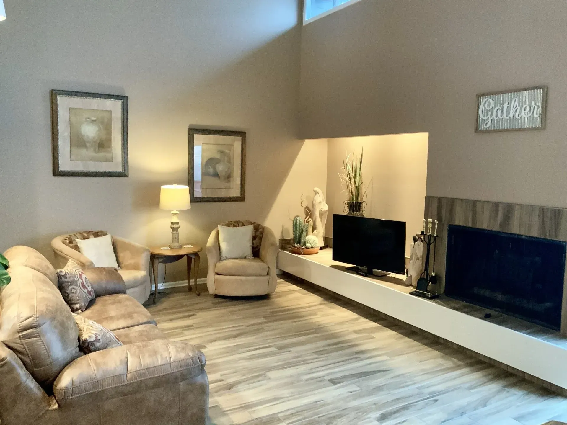 A living room with a couch , chair , television and fireplace.
