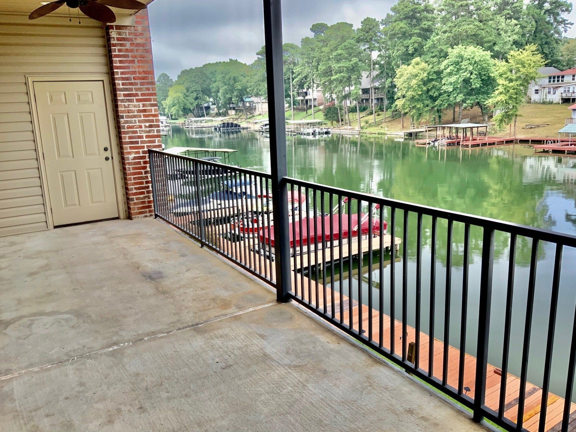 A patio with a railing overlooking a lake with boats docked.