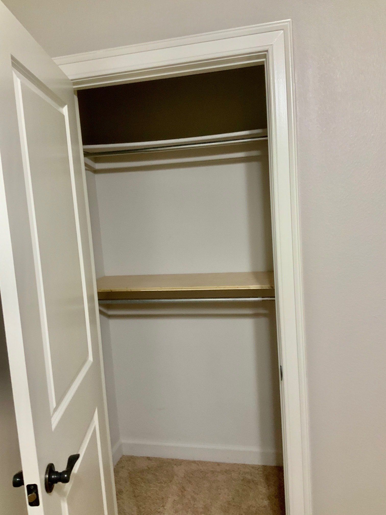 A closet with a door open and a shelf in it.
