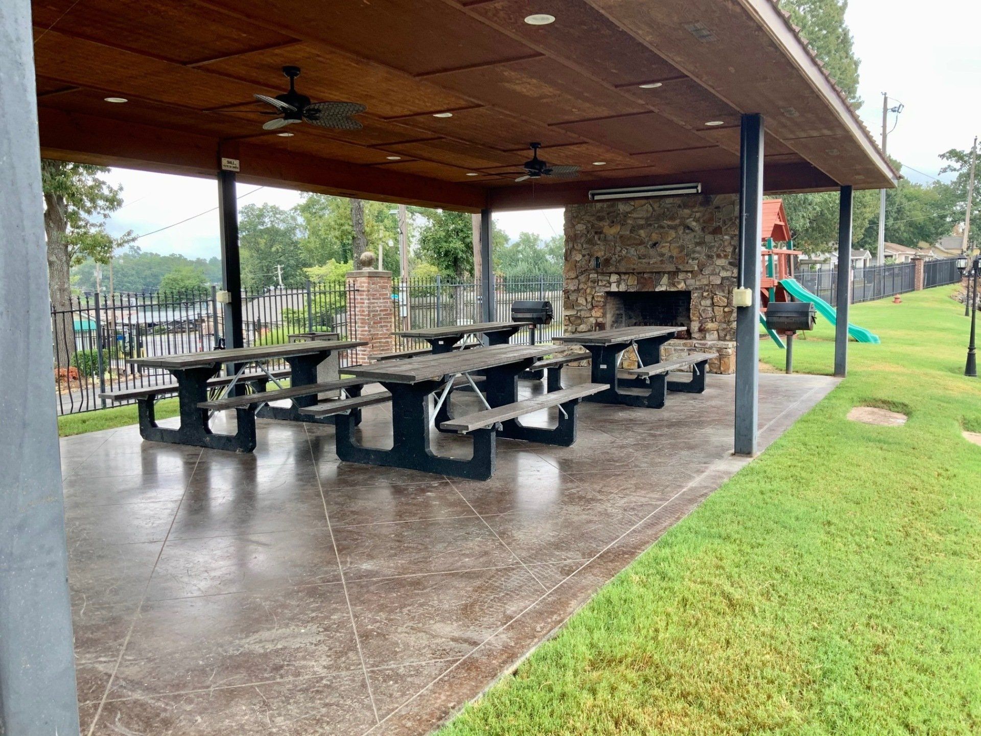 A group of picnic tables under a covered area in a park.