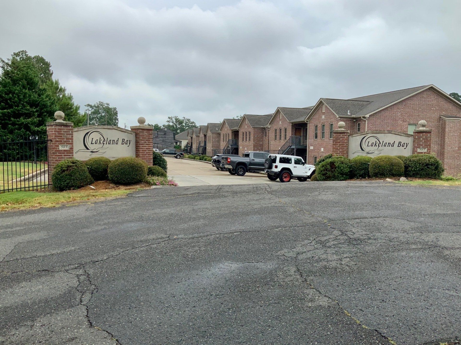 A row of brick buildings with cars parked in front of them.