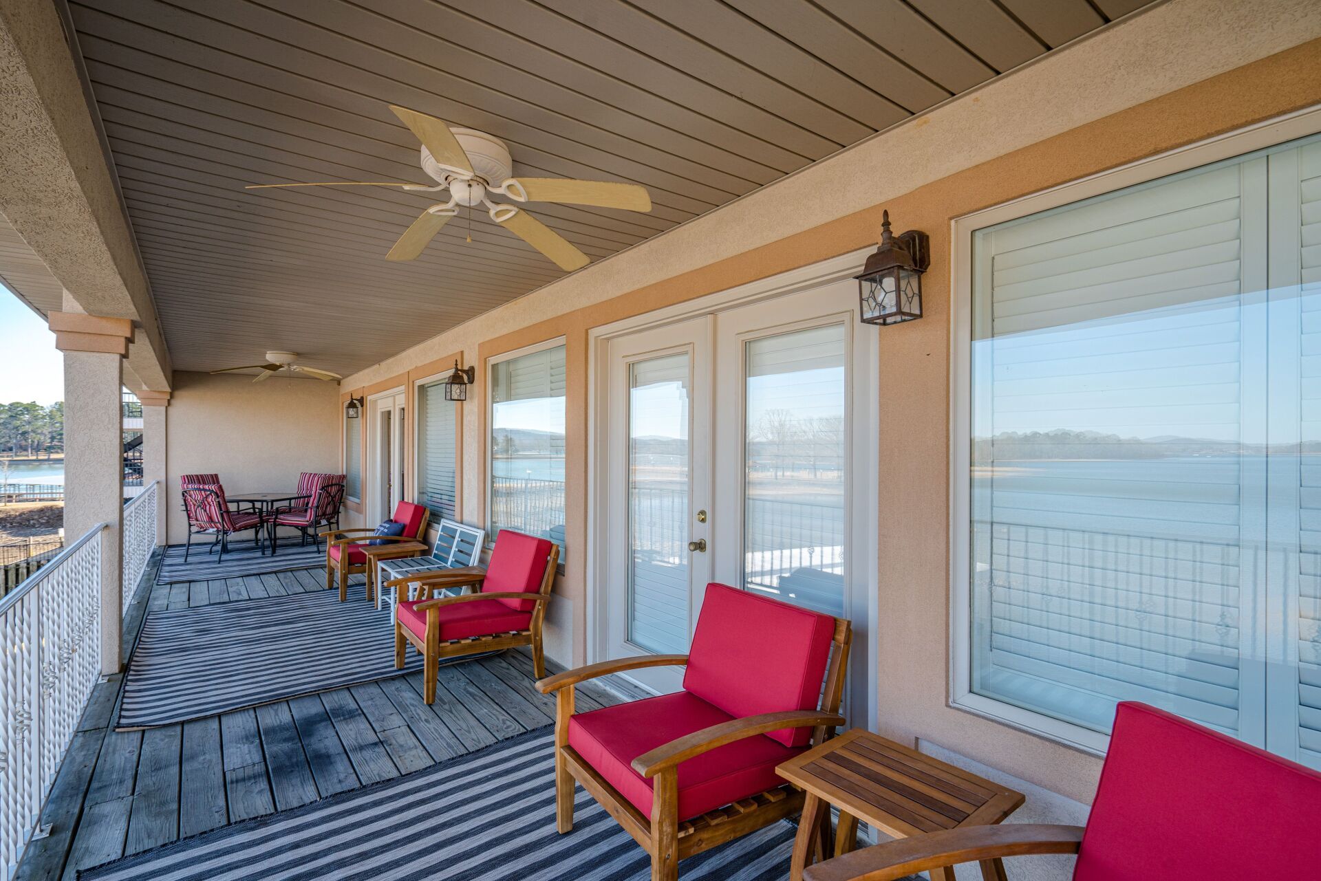 A balcony with red chairs and a ceiling fan overlooking the water.